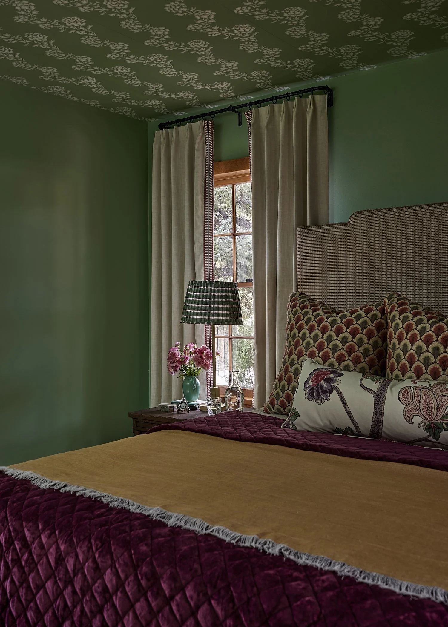 Bedroom with green walls, floral ceiling, and jewel-toned bedding, designed by French & French Interiors for a colorful Santa Fe home.