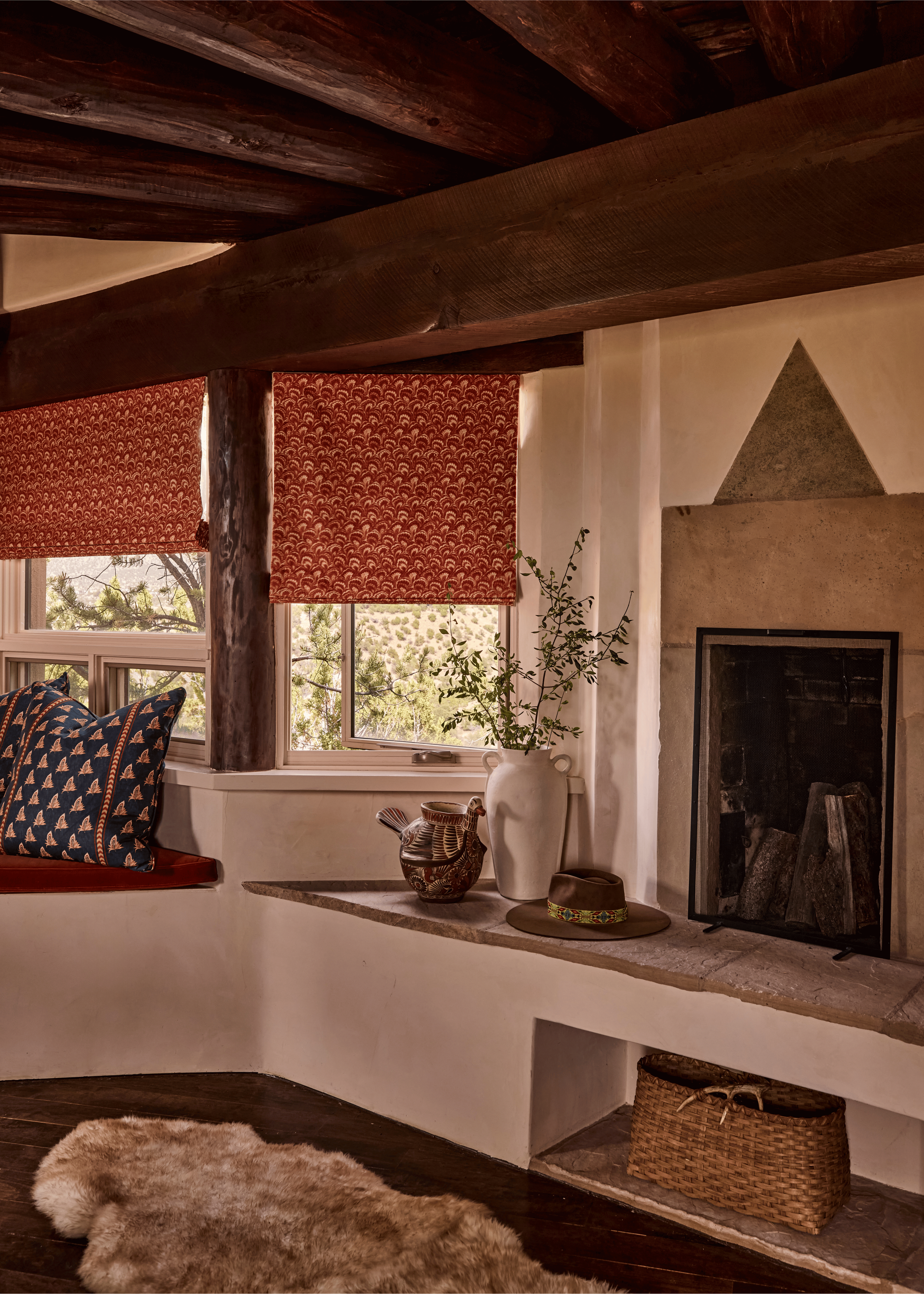 An adobe fireplace, dark vigas, and deep red block-print roman shades create the lodge-style warmth French & French Interiors set out to achieve at the Mesa Project - rich, soulful, and unmistakably rooted in the high desert of northern New Mexico.