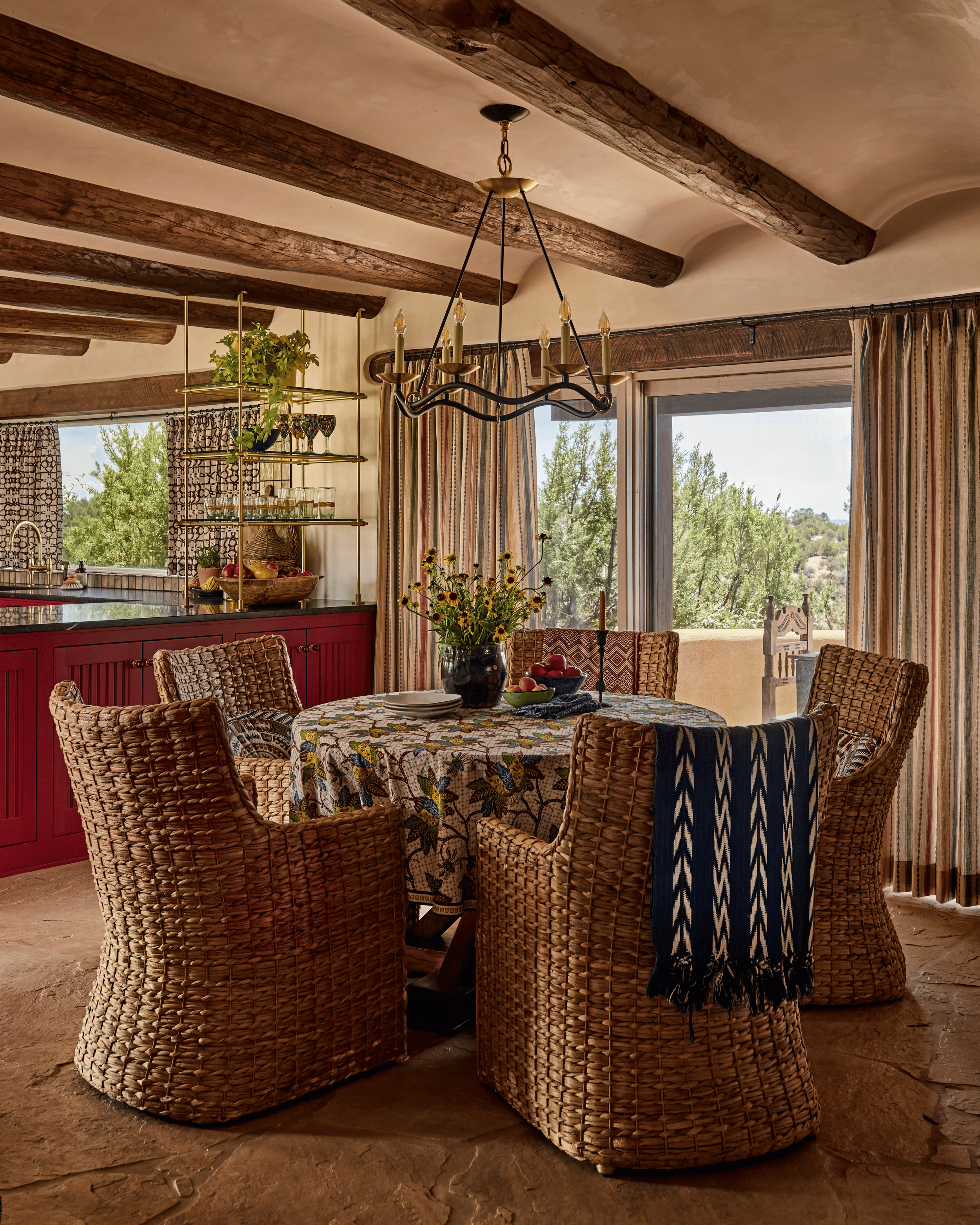 The dining table at the Mesa Project looks directly toward the Sangre de Cristo Mountains through a generous picture window - a view French & French Interiors made sure was never obscured, using linen drapes that frame rather than cover. The deep red