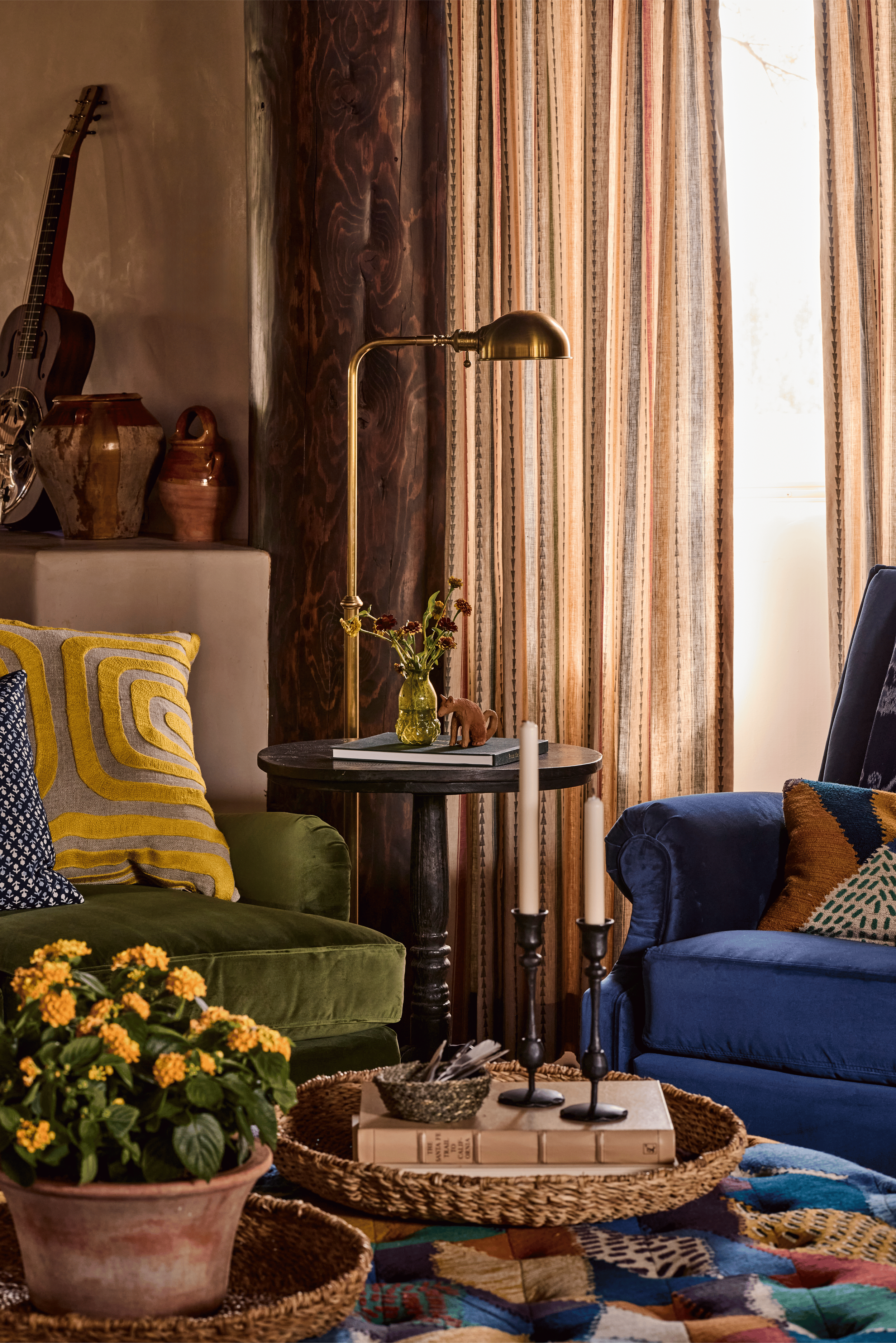 Forest green velvet, deep navy, striped linen drapes, and a vivid kilim rug come together in the living room of the Mesa Project - a room that proves bold color doesn't sacrifice warmth. French & French Interiors designed this space as a classic lodg