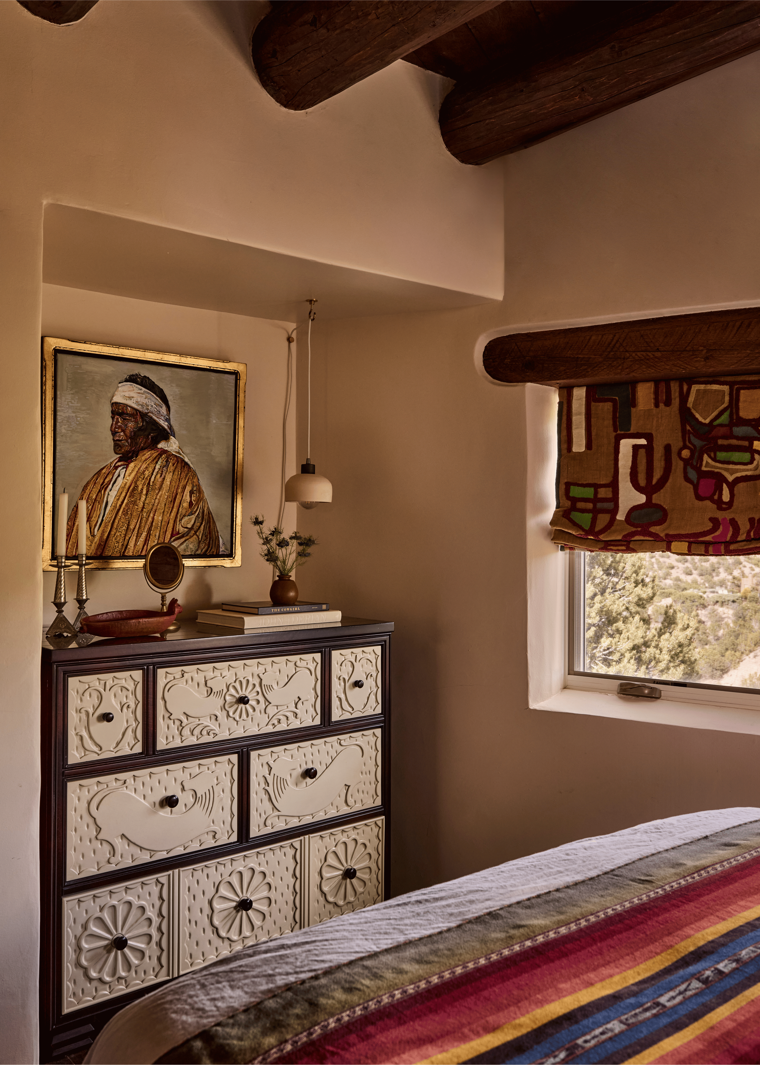 A carved folk-art dresser, a gilded portrait painting, and a graphic folk-print roman shade bring layered cultural depth to this bedroom at the Mesa Project - the kind of collected, meaningful maximalism that defines French & French Interiors' approa