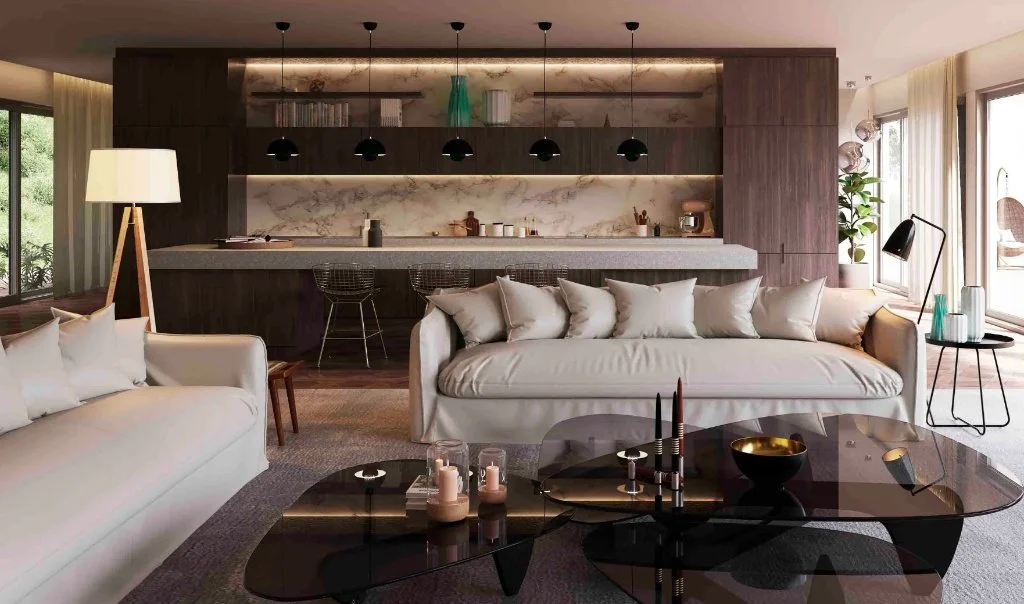 Wide view of a luxury interior in Girona showing a modern living area with beige sofas, smoked glass coffee tables, and a high-end integrated kitchen with a stone island and designer pendant lighting by Sebastian PM