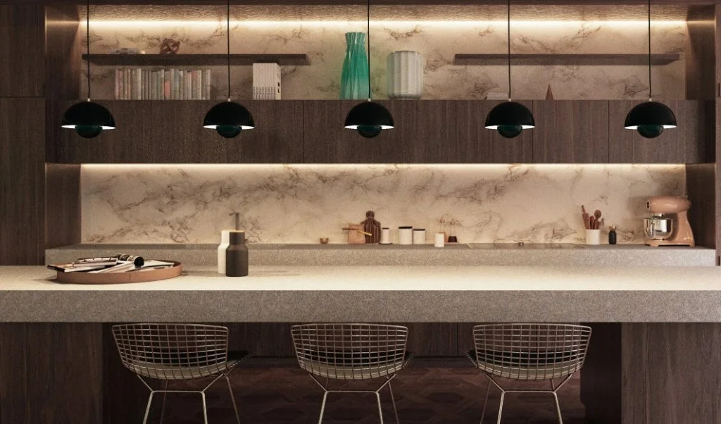 Close-up of a luxury kitchen in Girona featuring dark wood cabinetry, a marble backsplash with integrated lighting, and modern black pendant lamps over a stone island, designed by Sebastian PM
