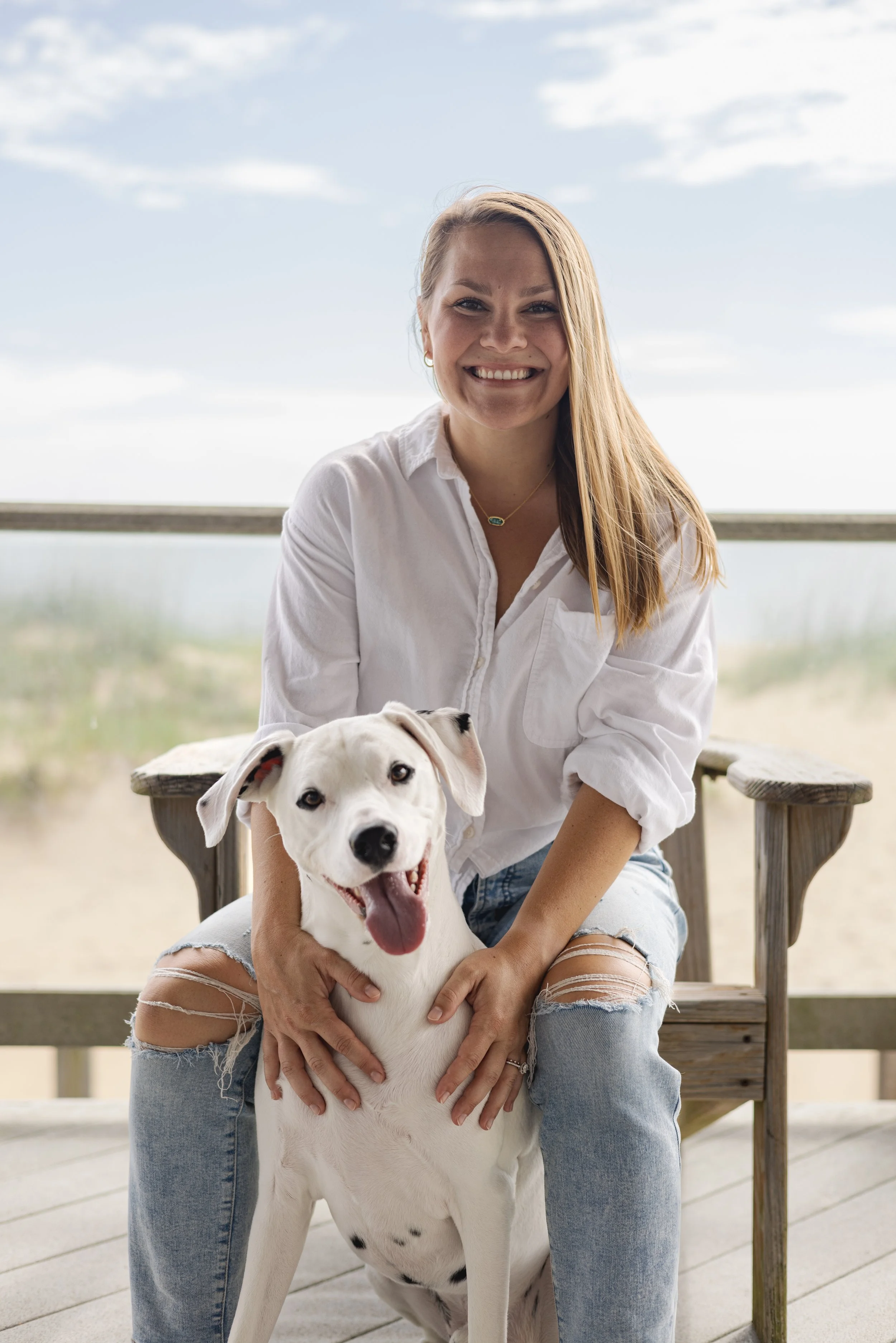 BUSINESS woman smiling at the beach with dalmatian dog
