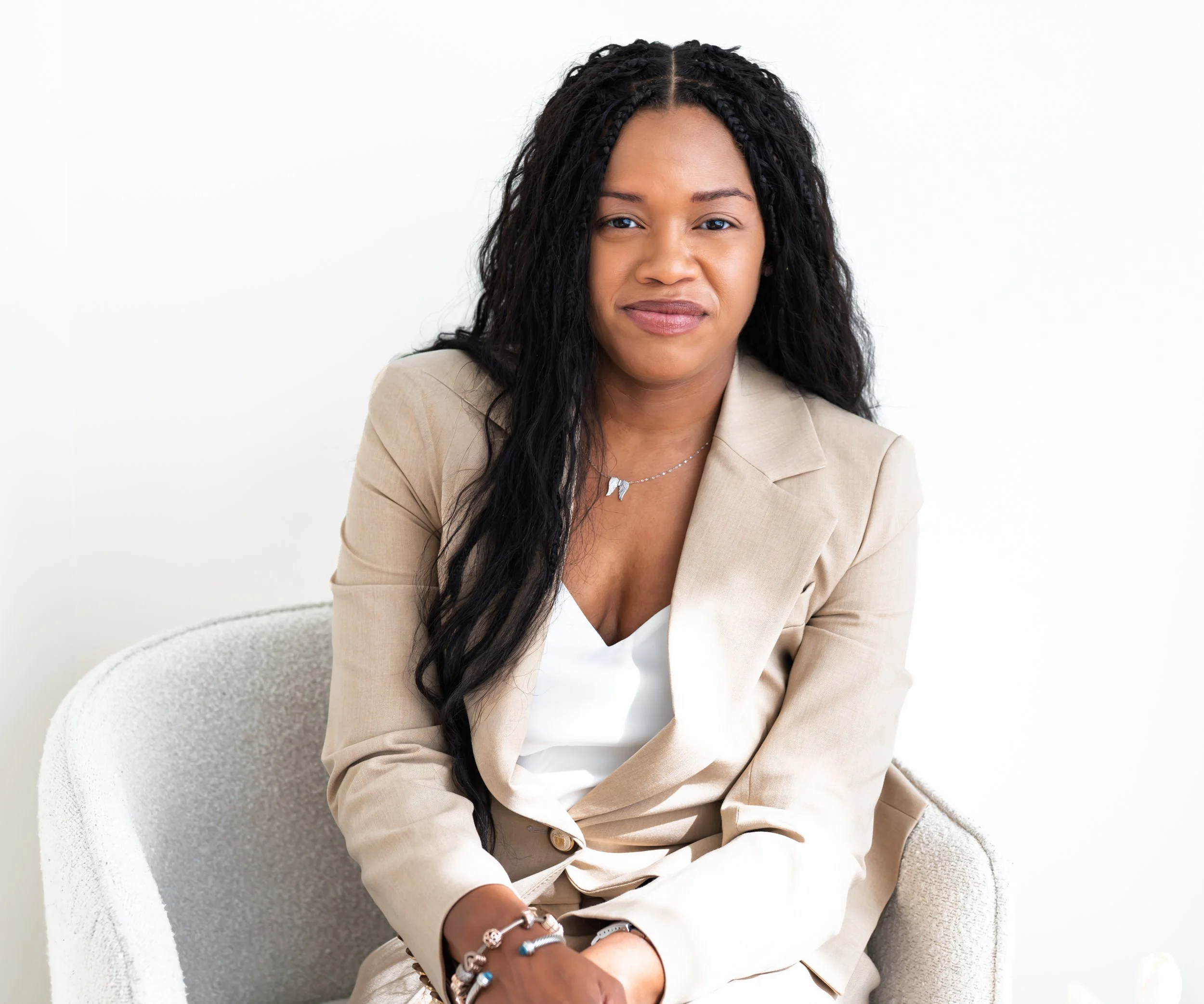 Sowania Germain, couples therapist in West Palm Beach, seated in an armchair in a tan suit