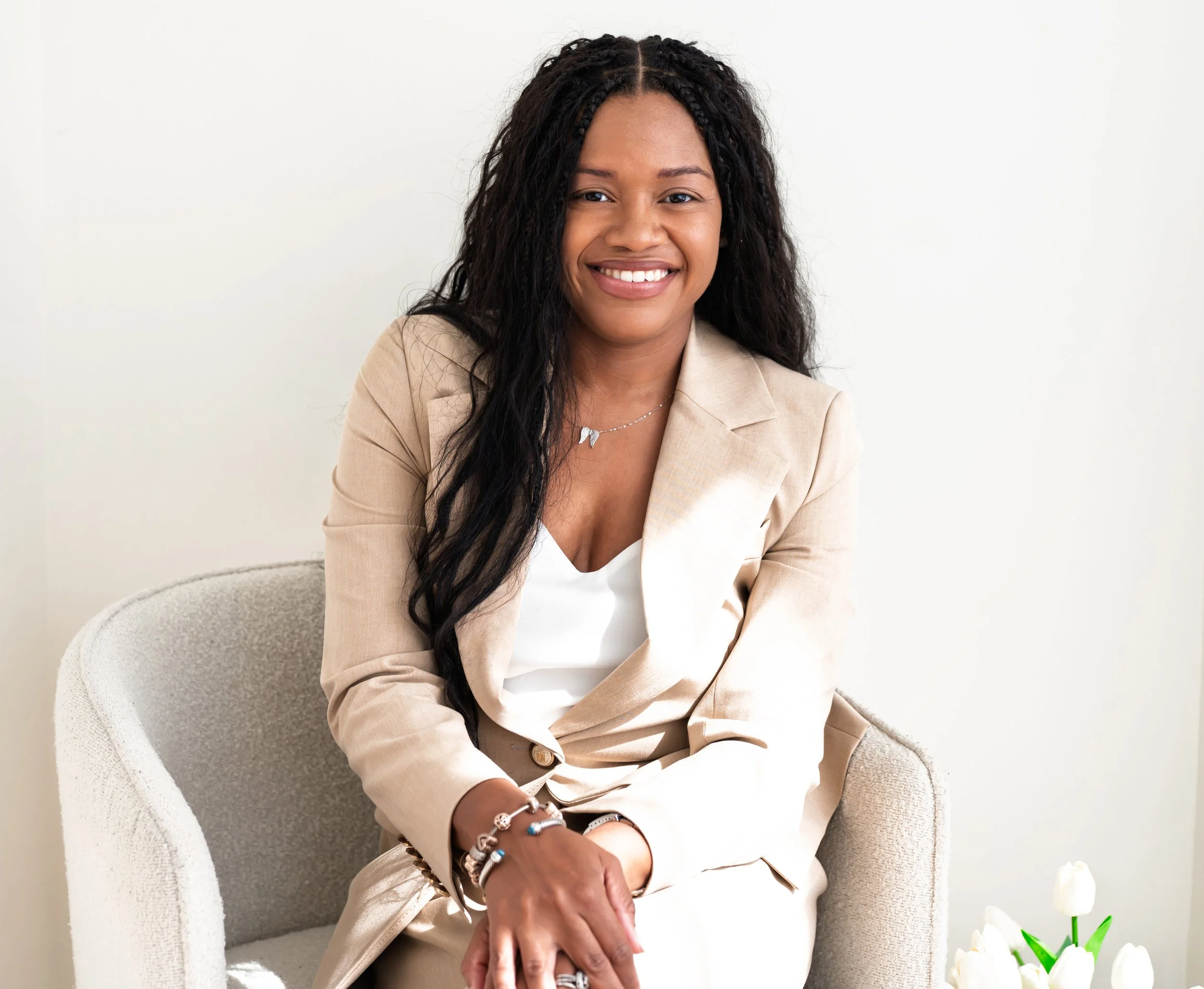 Sowania Germain, LMHC, offering EMDR intensives in West Palm Beach, smiling in a tan suit in an armchair