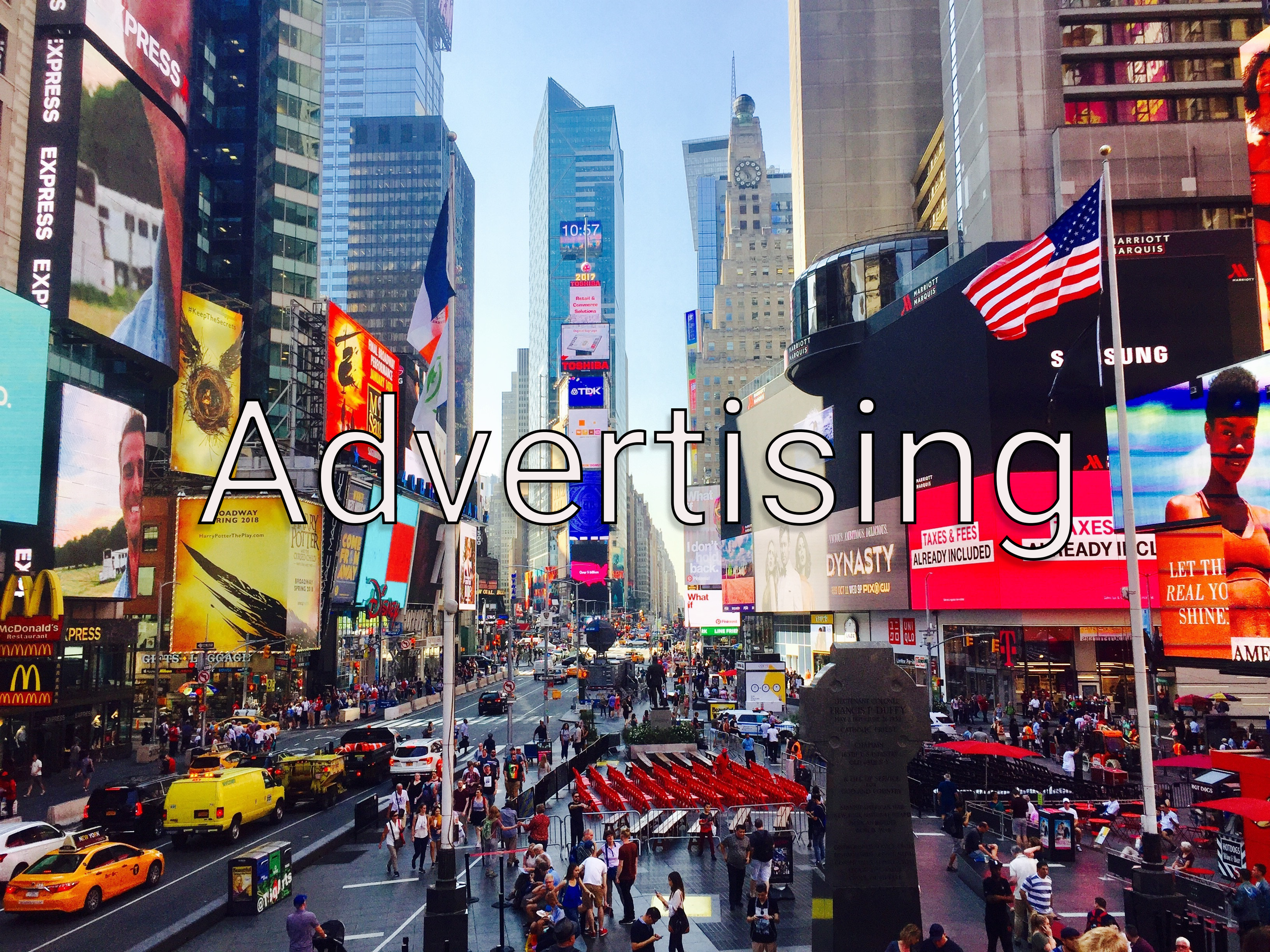 Times Square, New York City, with tall buildings, electronic billboards, people walking, and taxis.