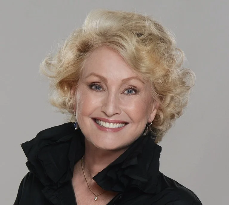 Smiling woman with curly blonde hair.