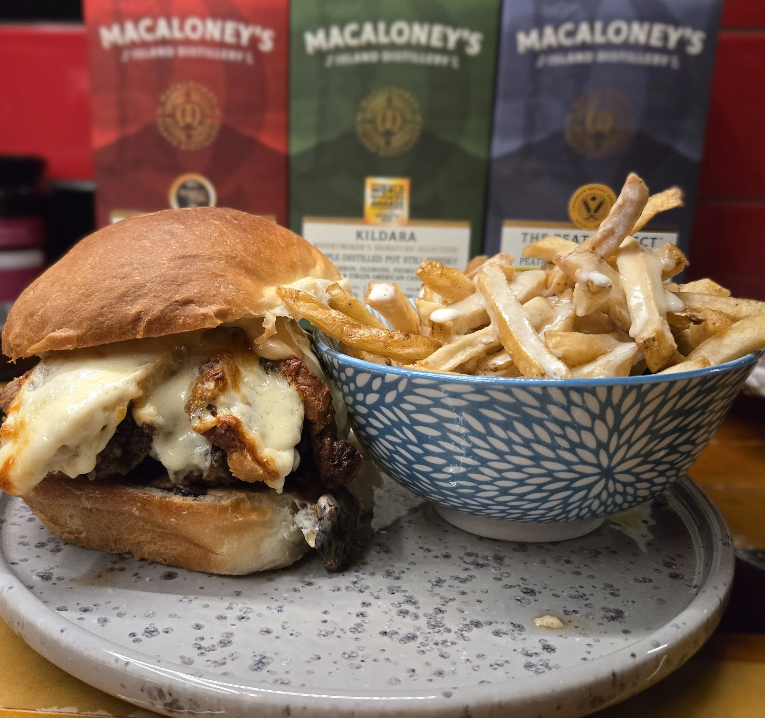 The Hanks 2.0 burger with melted cheese and house made bacon, served with a side of poutine.