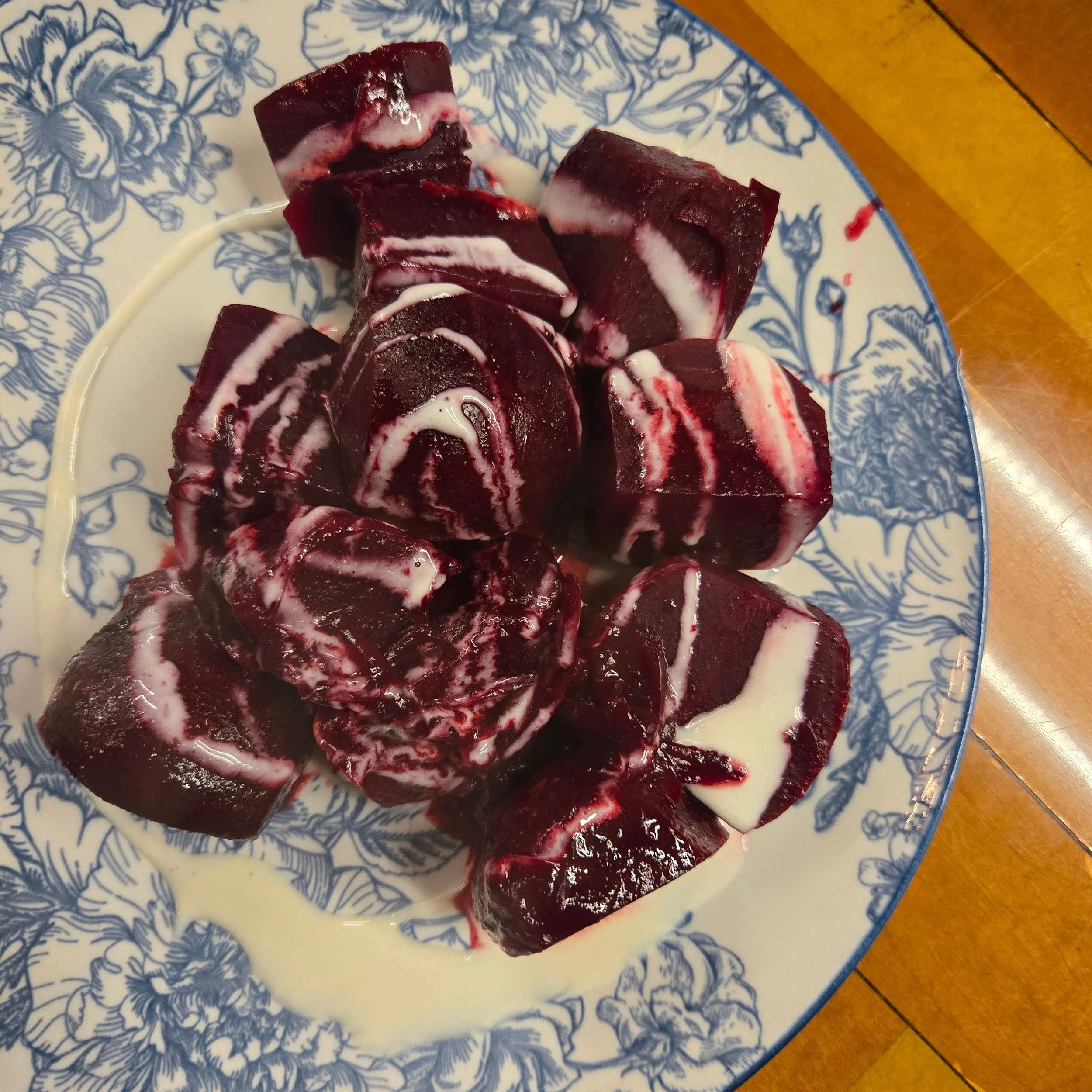 Square Root Farm beets, sous vide, serrano,  drizzled with farmhouse cheese sauce on a floral blue and white plate.