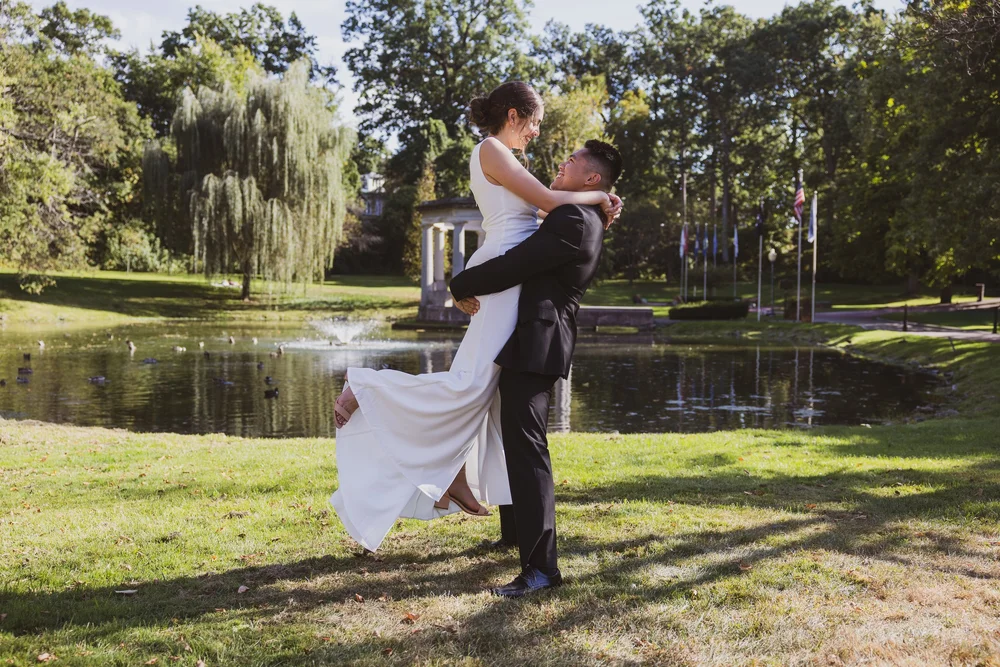 Groom lifting bride beside a pond