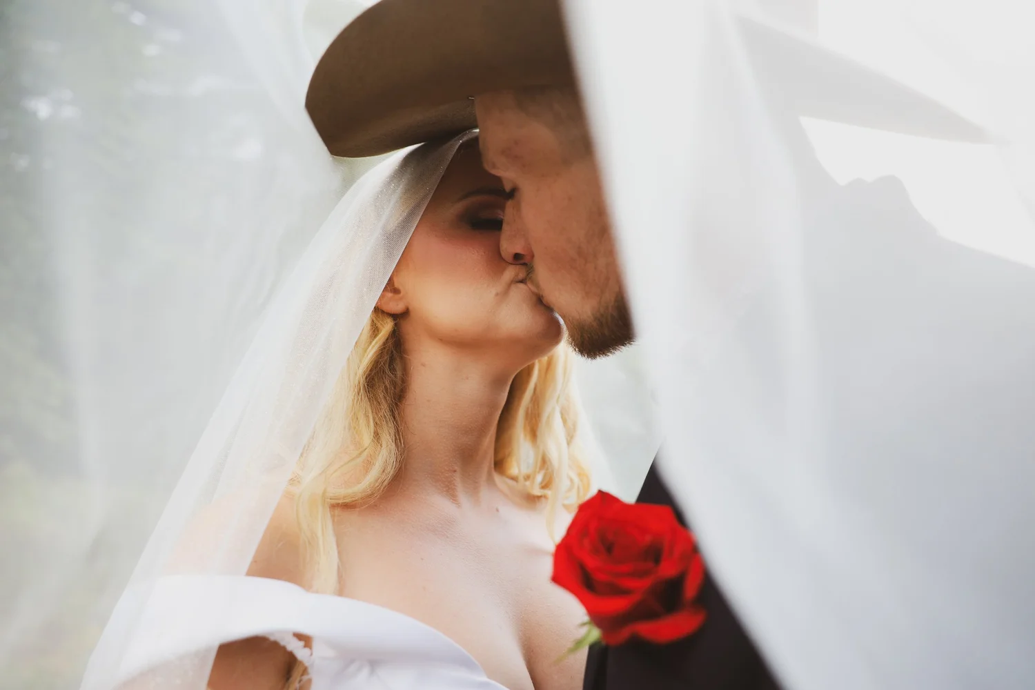 Bride and groom kissing beneath the wedding veil