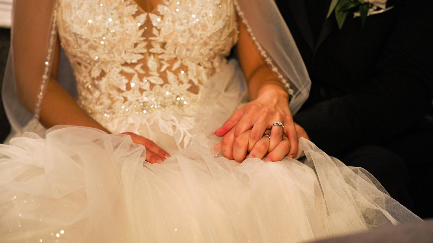 Newlyweds holding hands and showing wedding rings