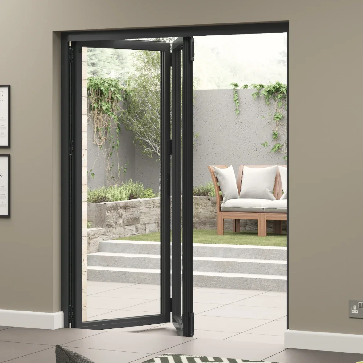 Open glass door leading to an outdoor patio with a bench, plants, shrubs, and a concrete wall.