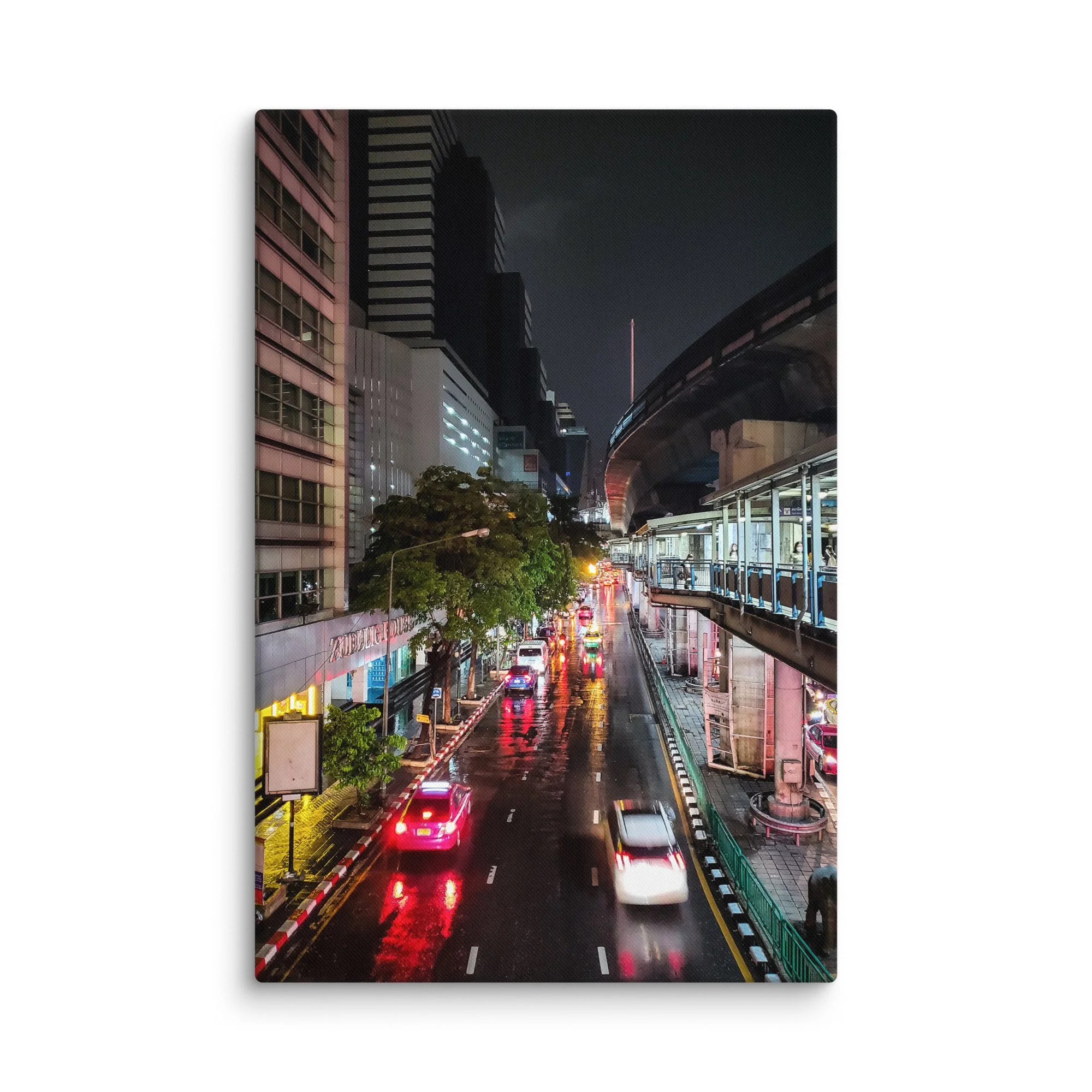 Rainy nighttime Bangkok street with wet reflections, neon lights, traffic and overhead BTS Skytrain – Thailand city travel photography canvas print wall art decor