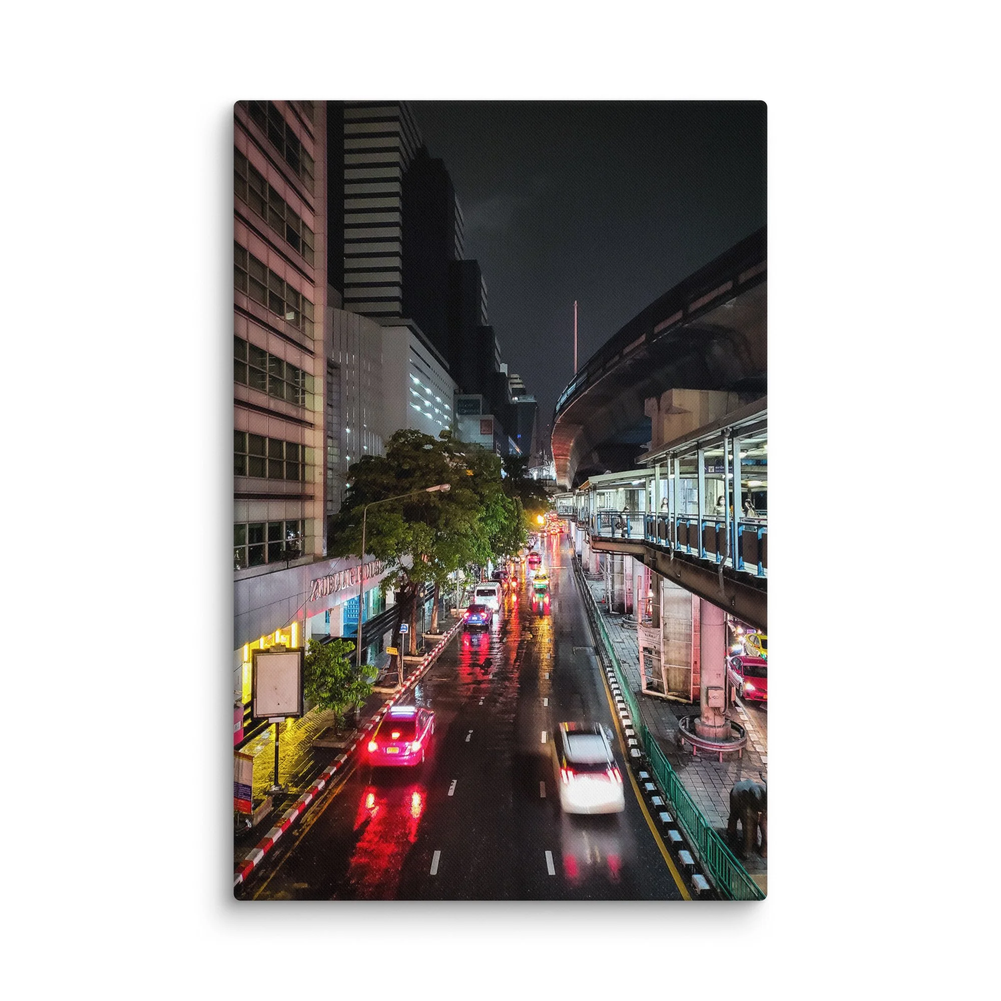 Rainy nighttime Bangkok street with wet reflections, neon lights, traffic and overhead BTS Skytrain – Thailand city travel photography canvas print wall art decor