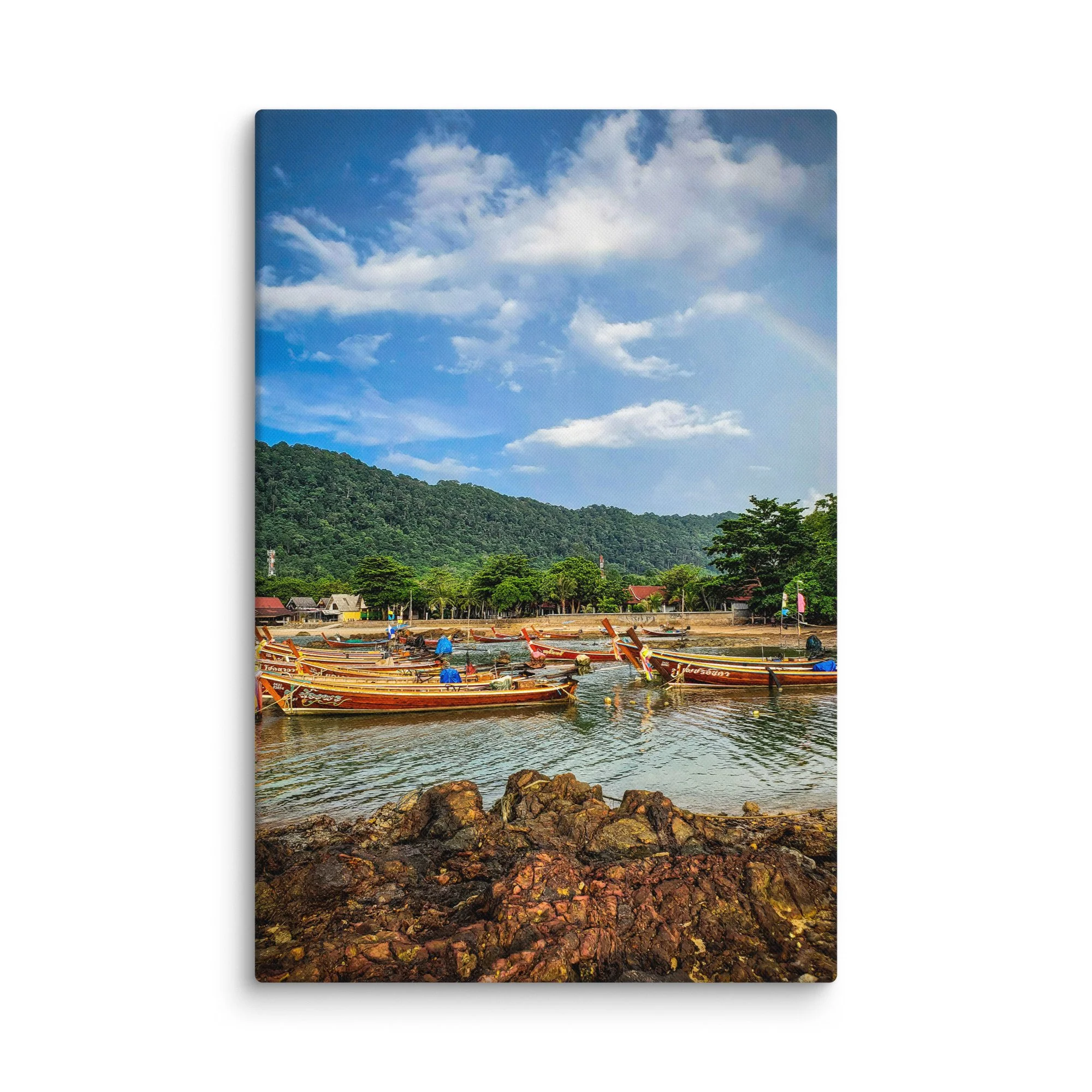Colorful longtail boats moored in shallow turquoise water at a quiet coastal village in Thailand with green hills and dramatic sky