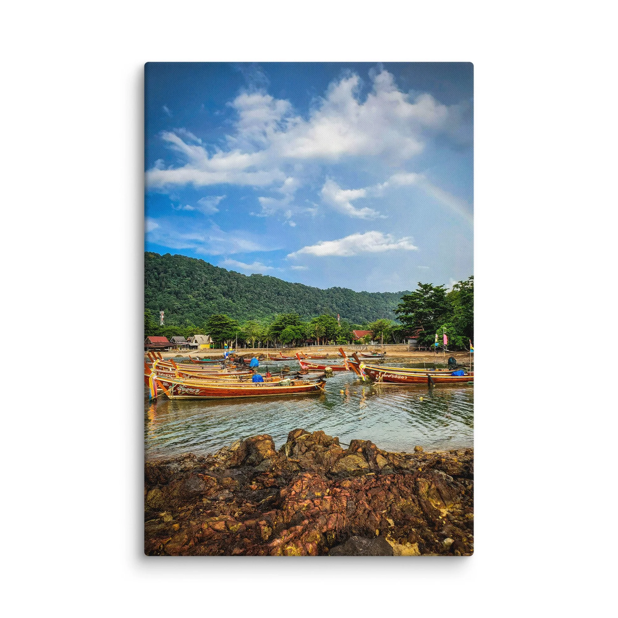 Colorful longtail boats moored in shallow turquoise water at a quiet coastal village in Thailand with green hills and dramatic sky