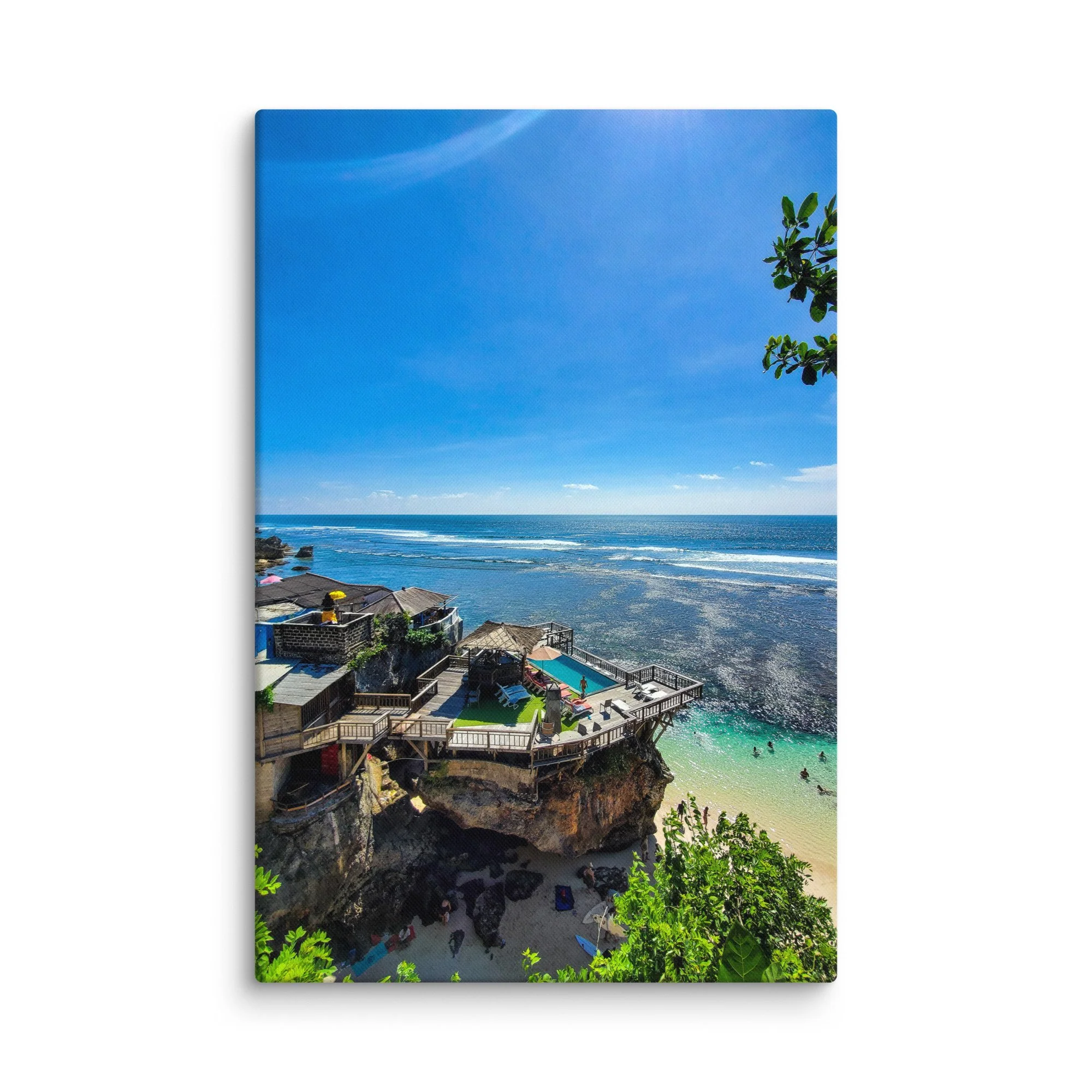 Stunning cliffside infinity pool and wooden platforms overlooking turquoise cove and ocean in Bali, Indonesia under bright blue sky