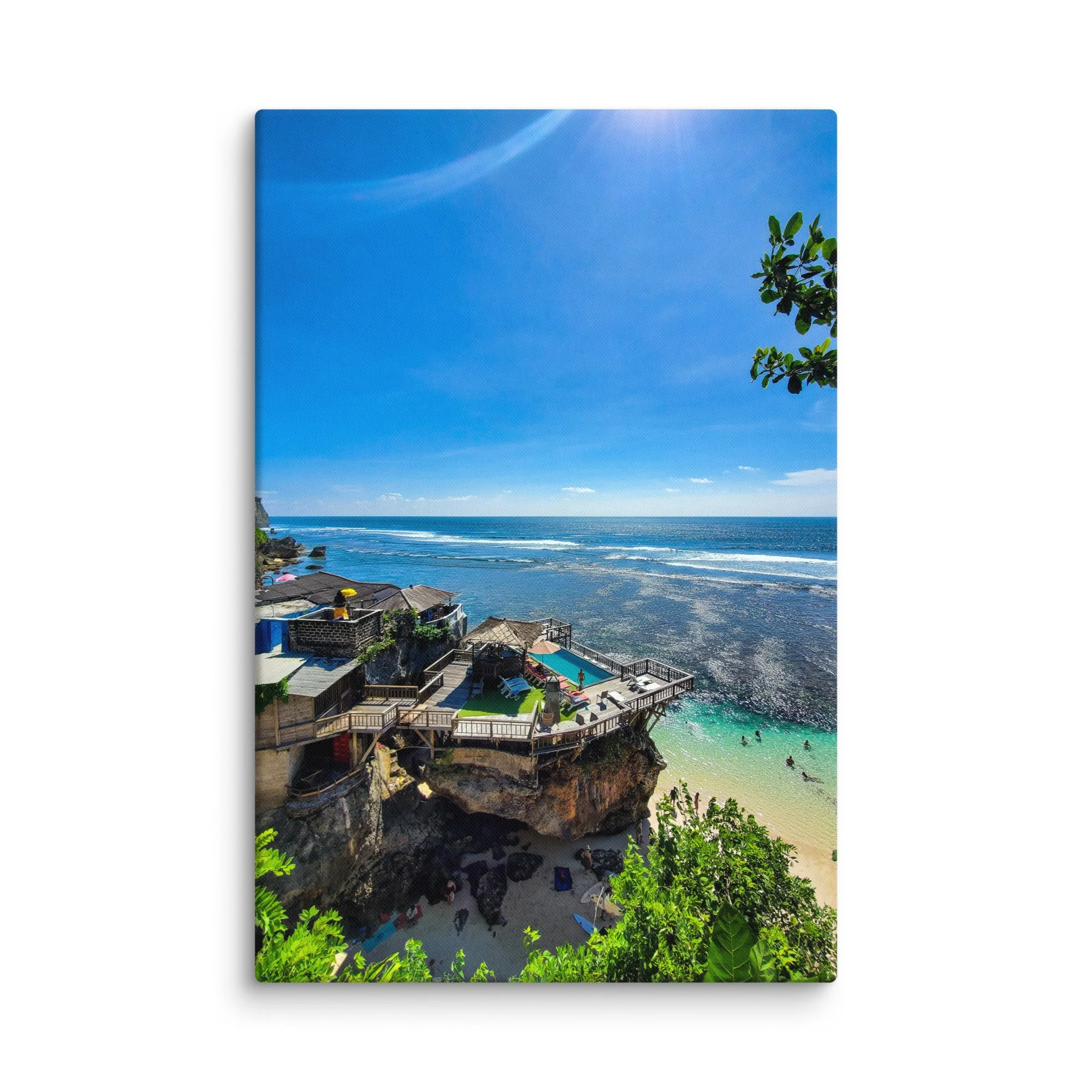 Stunning cliffside infinity pool and wooden platforms overlooking turquoise cove and ocean in Bali, Indonesia under bright blue sky