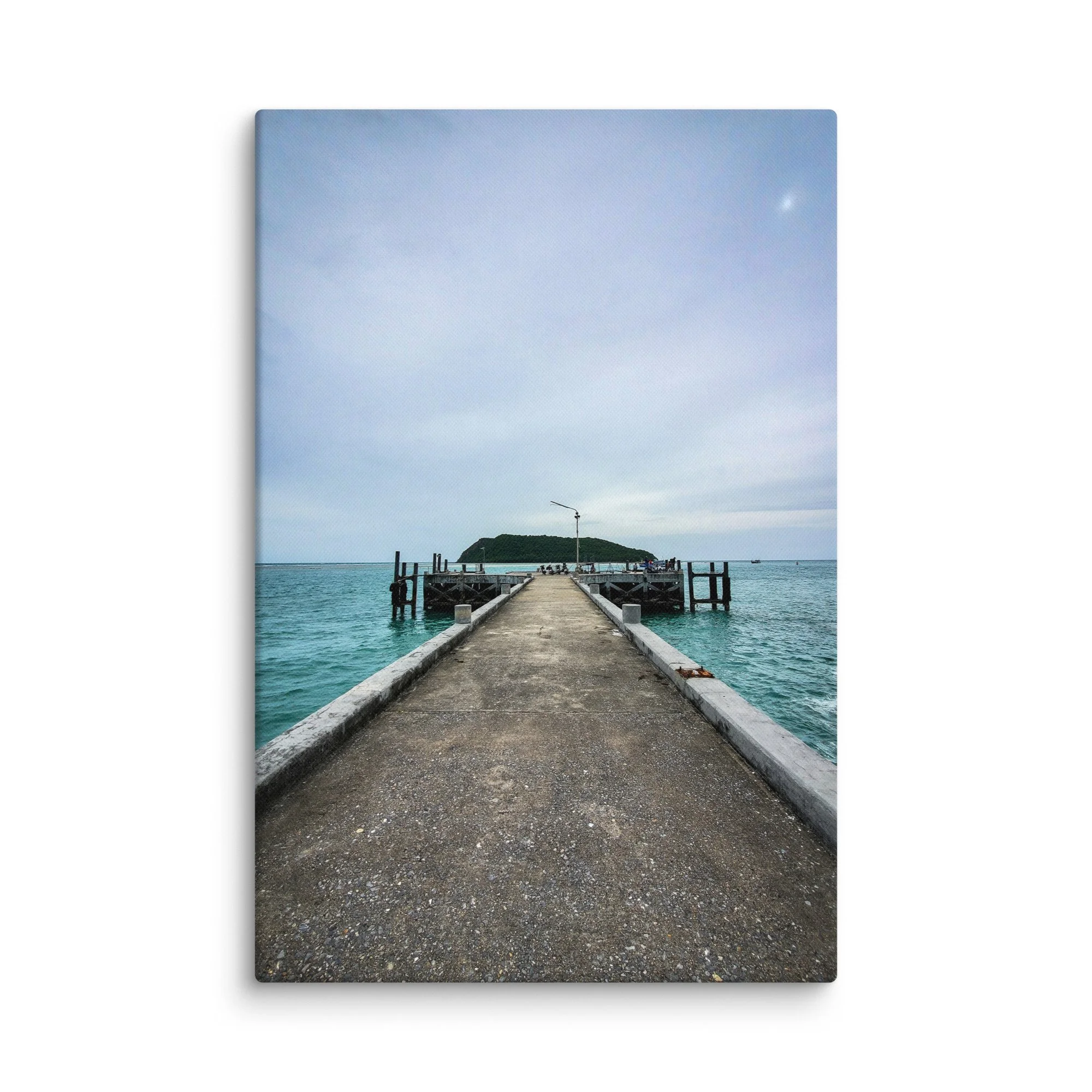 Long wooden pier extending into calm turquoise waters with overhanging foliage and distant green island in Thailand – tropical travel photography canvas print wall art decor