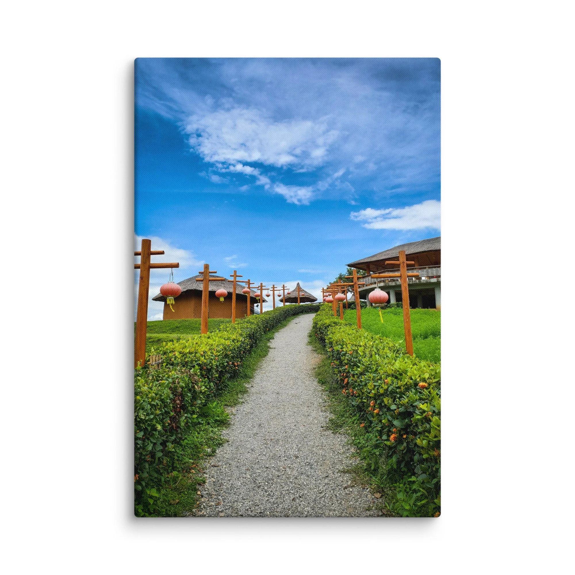 Gravel path lined with pink lanterns leading through thatched-roof resort huts under bright blue sky in Thailand – tropical travel photography canvas print wall art decor