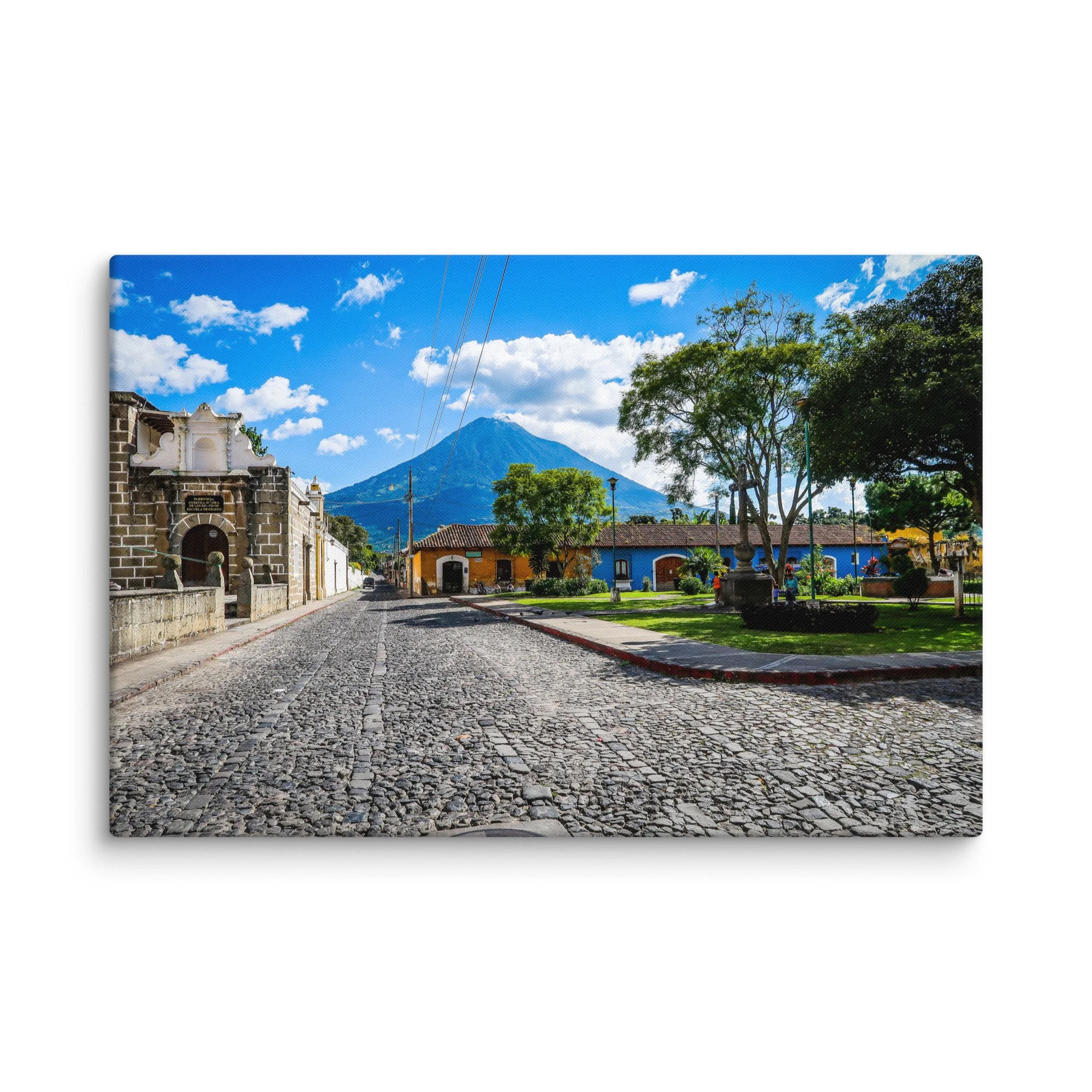 Iconic cobblestone street in Antigua Guatemala with colorful colonial buildings and towering Volcán de Agua under blue sky – cultural travel photography canvas print wall art decor