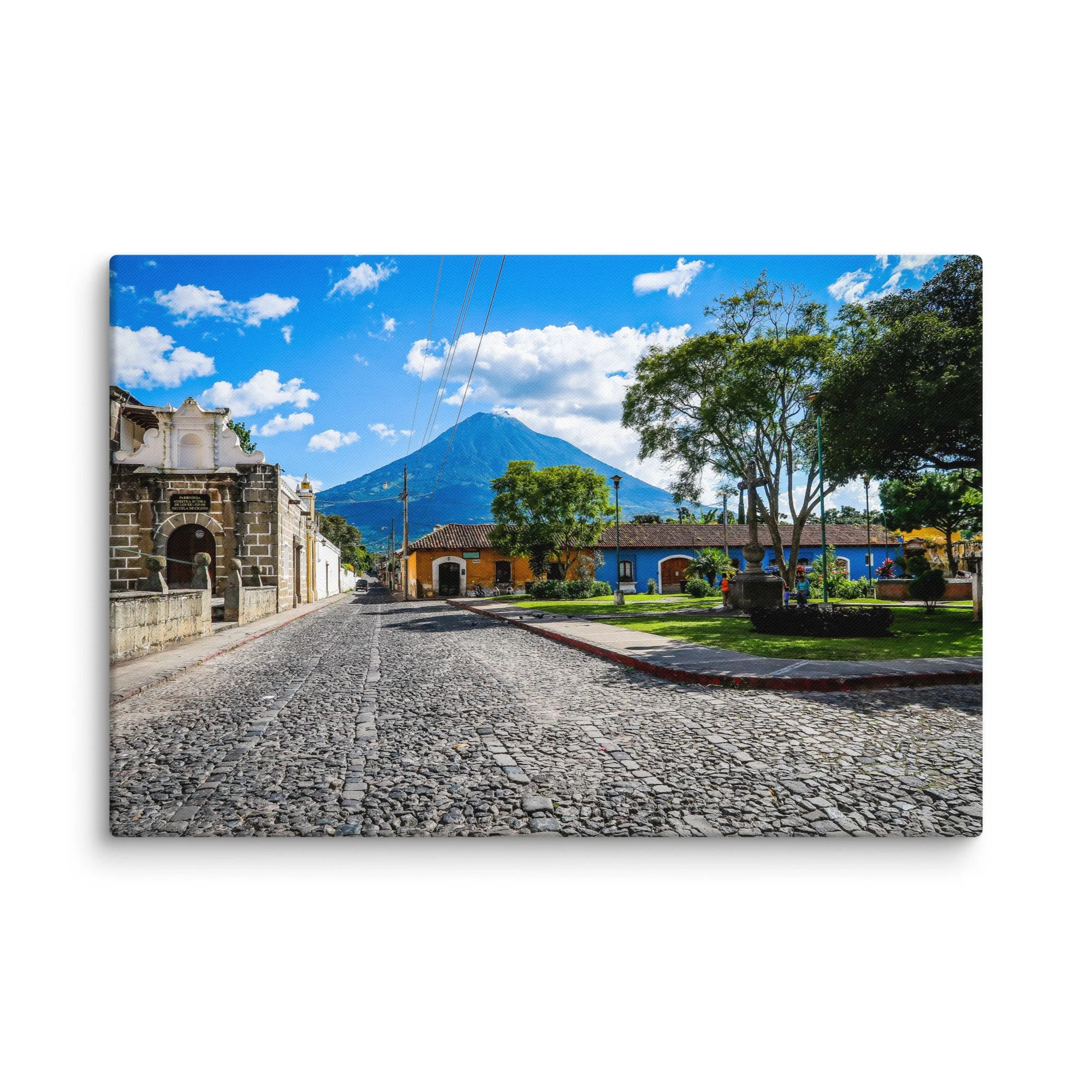 Iconic cobblestone street in Antigua Guatemala with colorful colonial buildings and towering Volcán de Agua under blue sky – cultural travel photography canvas print wall art decor