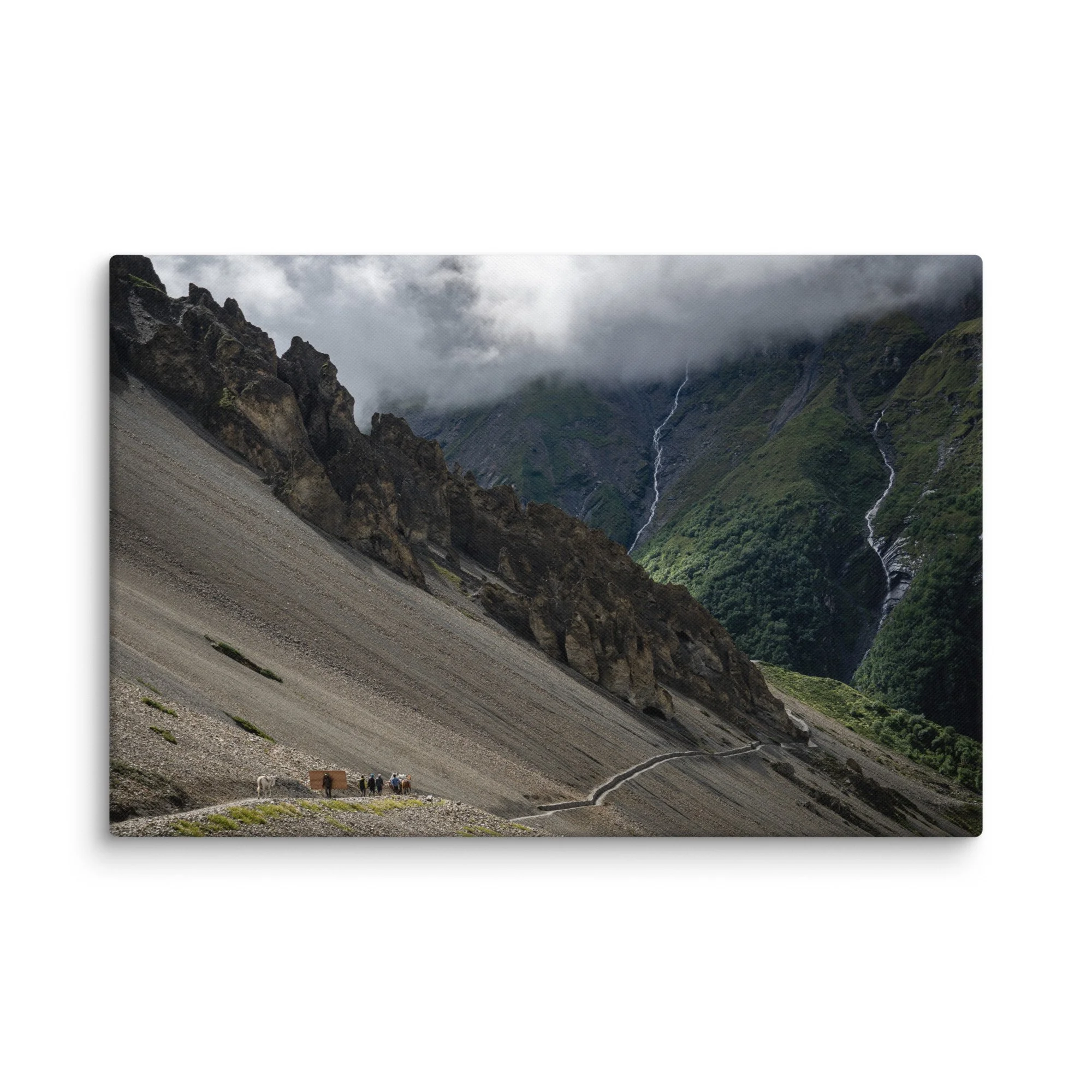 Trekkers with mules descending a steep rocky trail on the Annapurna Circuit, Nepal, with dramatic Himalayan peaks, waterfalls and moody sky – high-altitude trekking travel photography