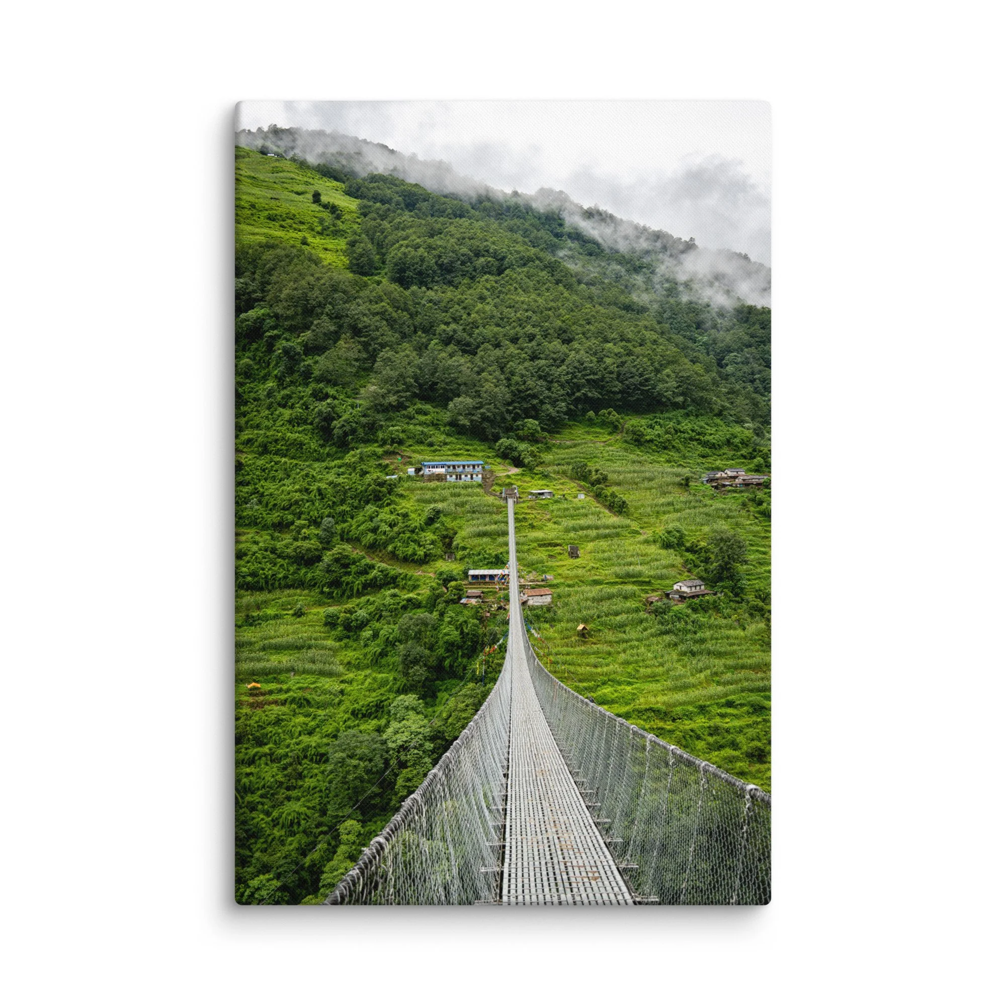 Long suspension bridge crossing a lush green valley on the Annapurna Circuit, Nepal with misty hills, villages and Himalayan peaks – high-altitude trekking travel photography canvas print