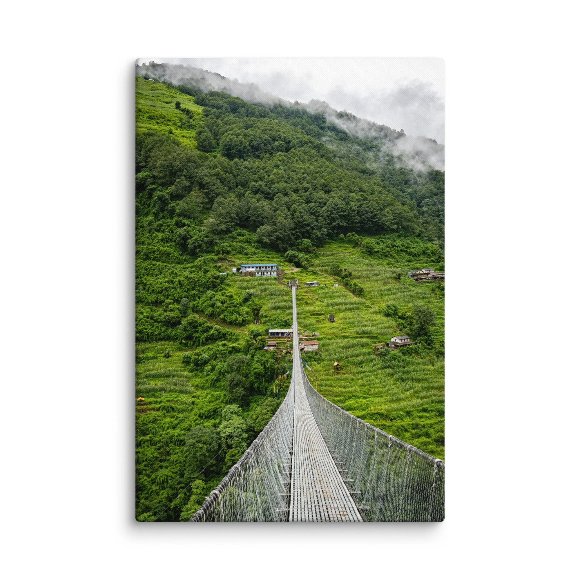 Long suspension bridge crossing a lush green valley on the Annapurna Circuit, Nepal with misty hills, villages and Himalayan peaks – high-altitude trekking travel photography canvas print