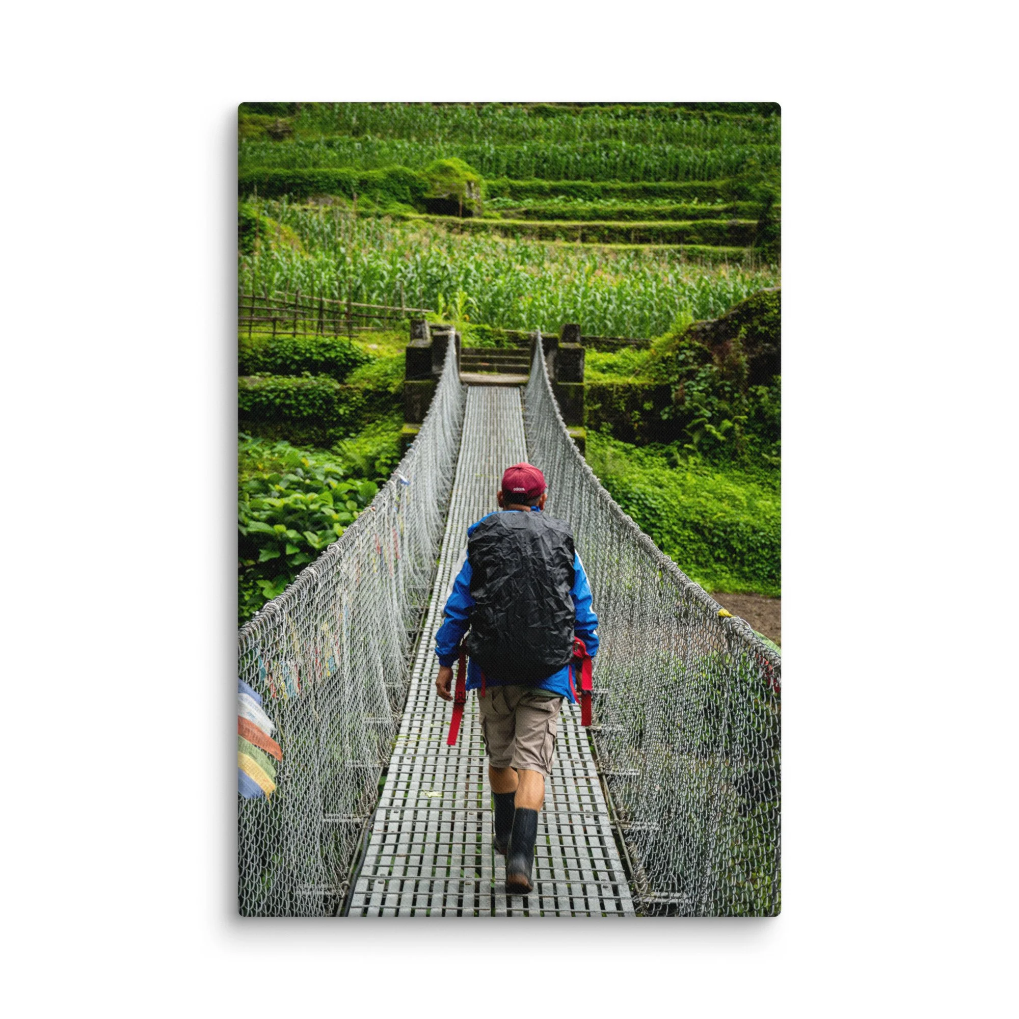 Trekker crossing a long suspension bridge over lush green rice terraces on the Annapurna Circuit, Nepal with misty hills and Himalayan peaks – high-altitude trekking travel photography