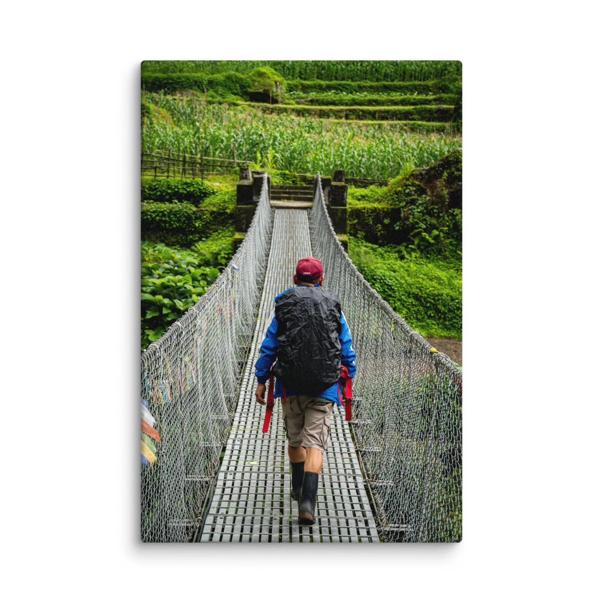 Trekker crossing a long suspension bridge over lush green rice terraces on the Annapurna Circuit, Nepal with misty hills and Himalayan peaks – high-altitude trekking travel photography