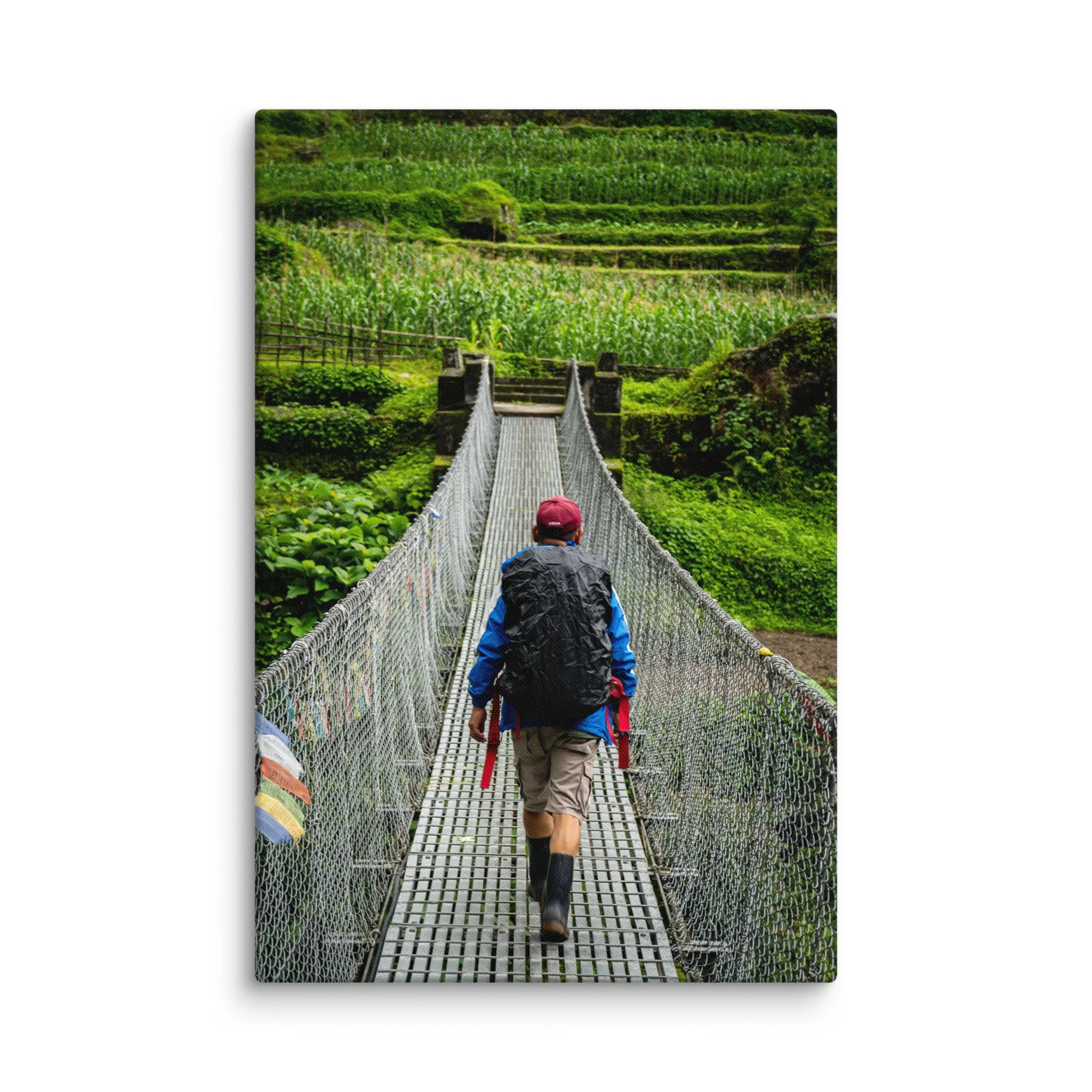 Trekker crossing a long suspension bridge over lush green rice terraces on the Annapurna Circuit, Nepal with misty hills and Himalayan peaks – high-altitude trekking travel photography