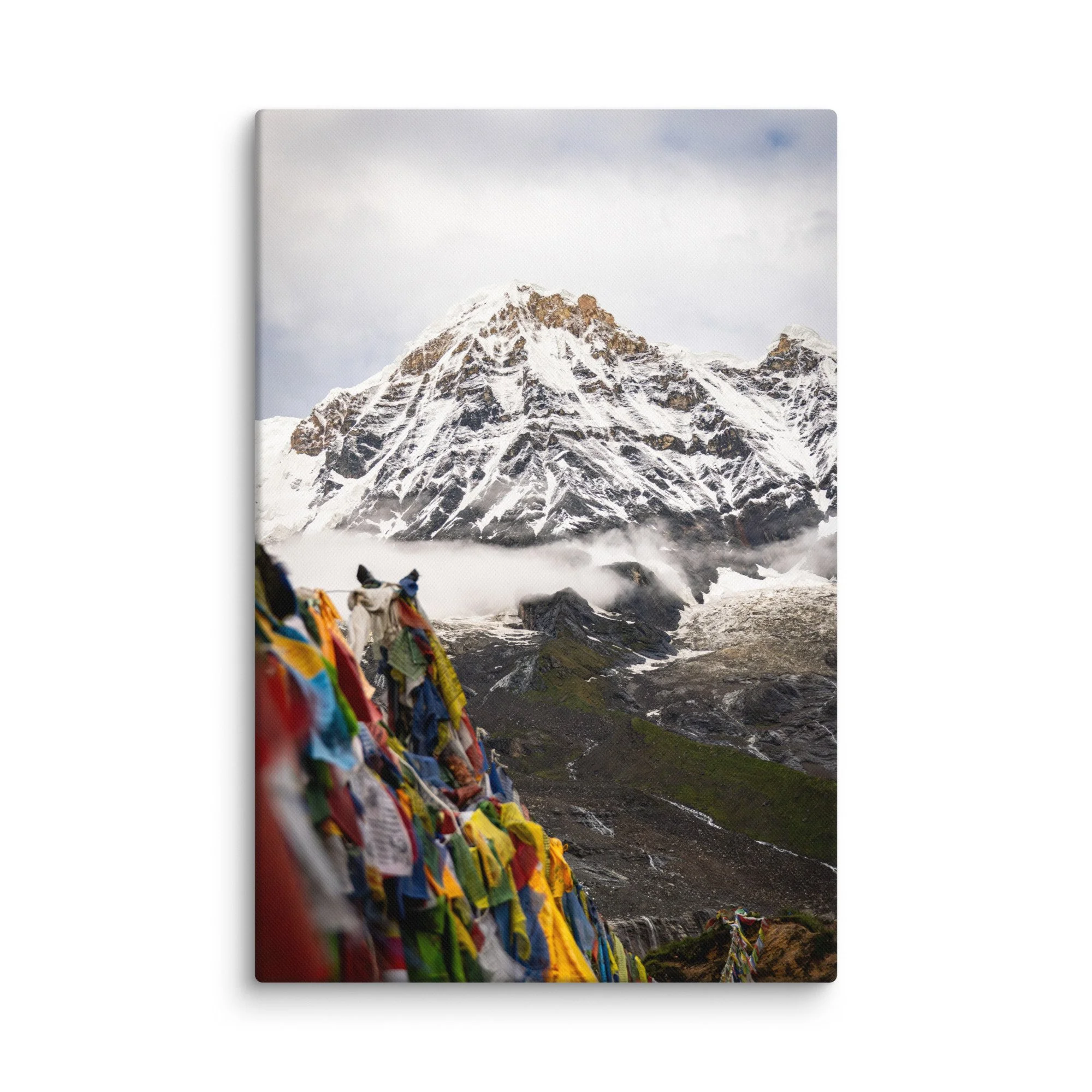 Vibrant multicolored prayer flags in the foreground with towering snow-covered Himalayan peaks and misty sky on the Annapurna Circuit, Nepal – high-altitude spiritual trekking travel