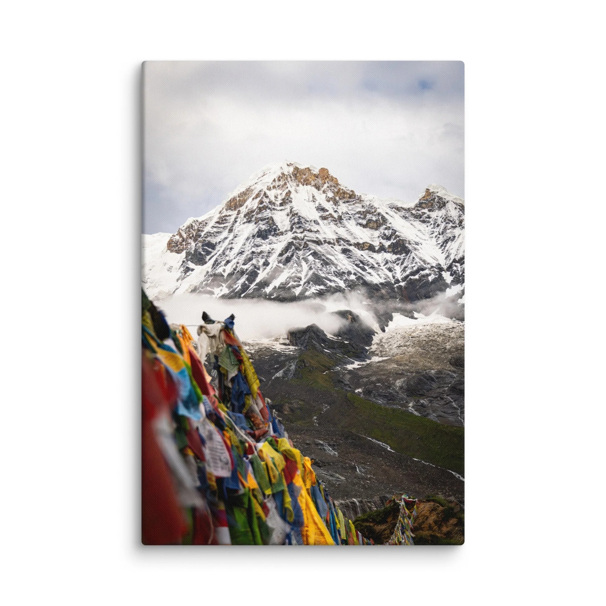 Vibrant multicolored prayer flags in the foreground with towering snow-covered Himalayan peaks and misty sky on the Annapurna Circuit, Nepal – high-altitude spiritual trekking travel