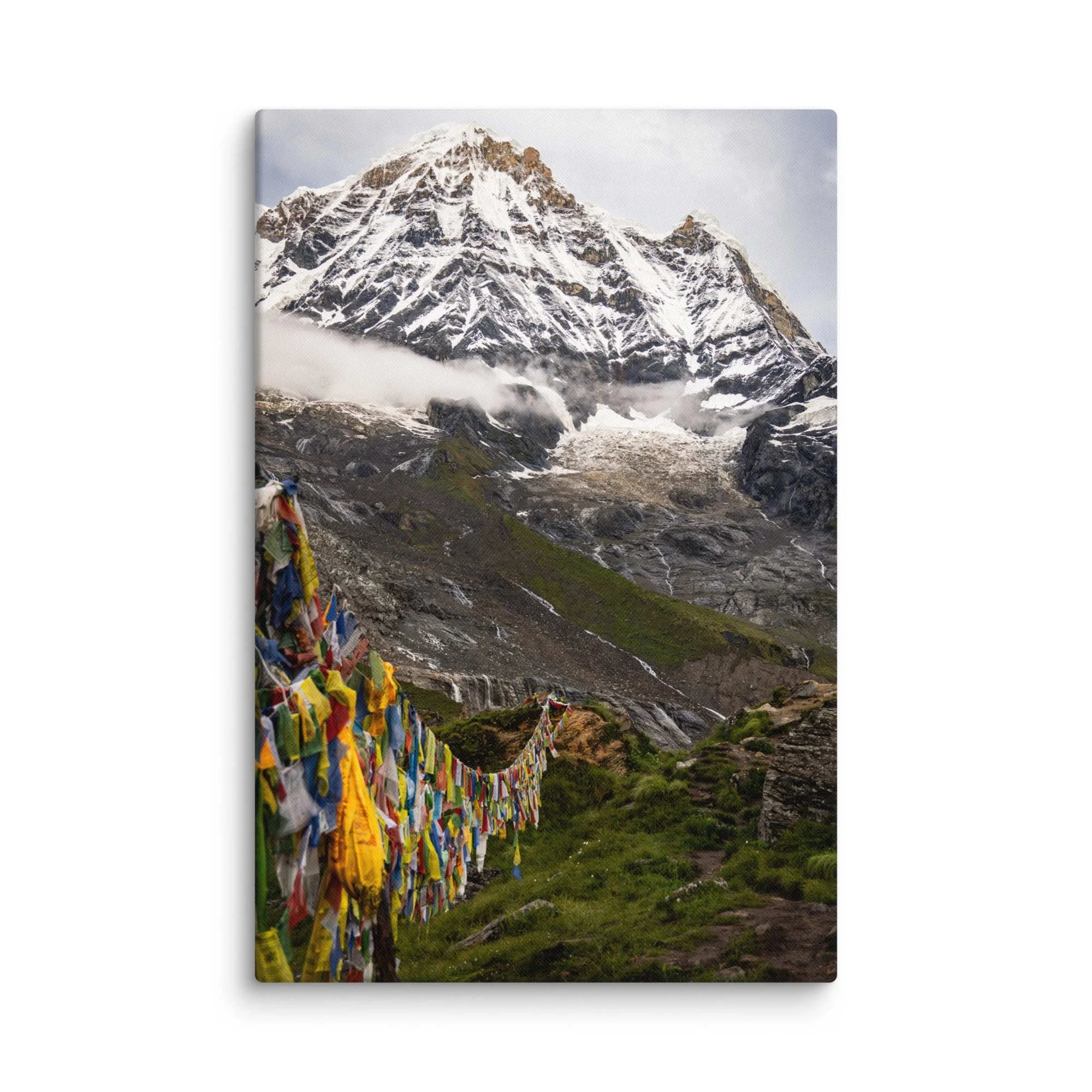 Vibrant multicolored prayer flags fluttering in the foreground with towering snow-covered Himalayan peaks and misty sky at Annapurna Base Camp, Nepal – high-altitude spiritual trekking