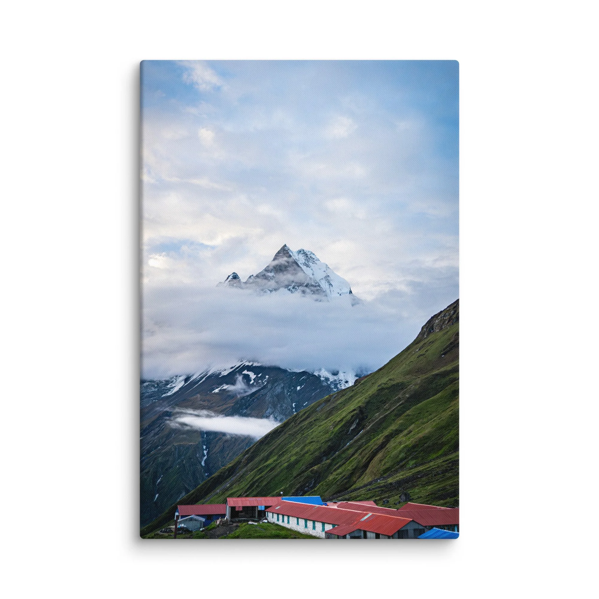 Colorful teahouses and lodges with red and blue roofs nestled in the green slopes below towering snow-covered Himalayan peaks at Annapurna Base Camp, Nepal – high-altitude trekking