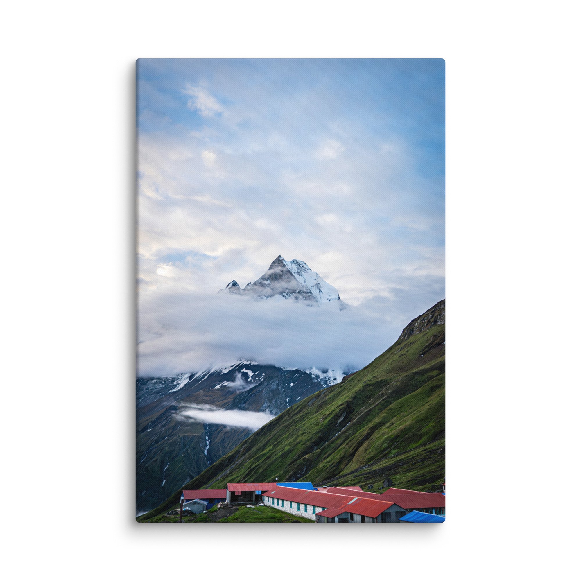 Colorful teahouses and lodges with red and blue roofs nestled in the green slopes below towering snow-covered Himalayan peaks at Annapurna Base Camp, Nepal – high-altitude trekking