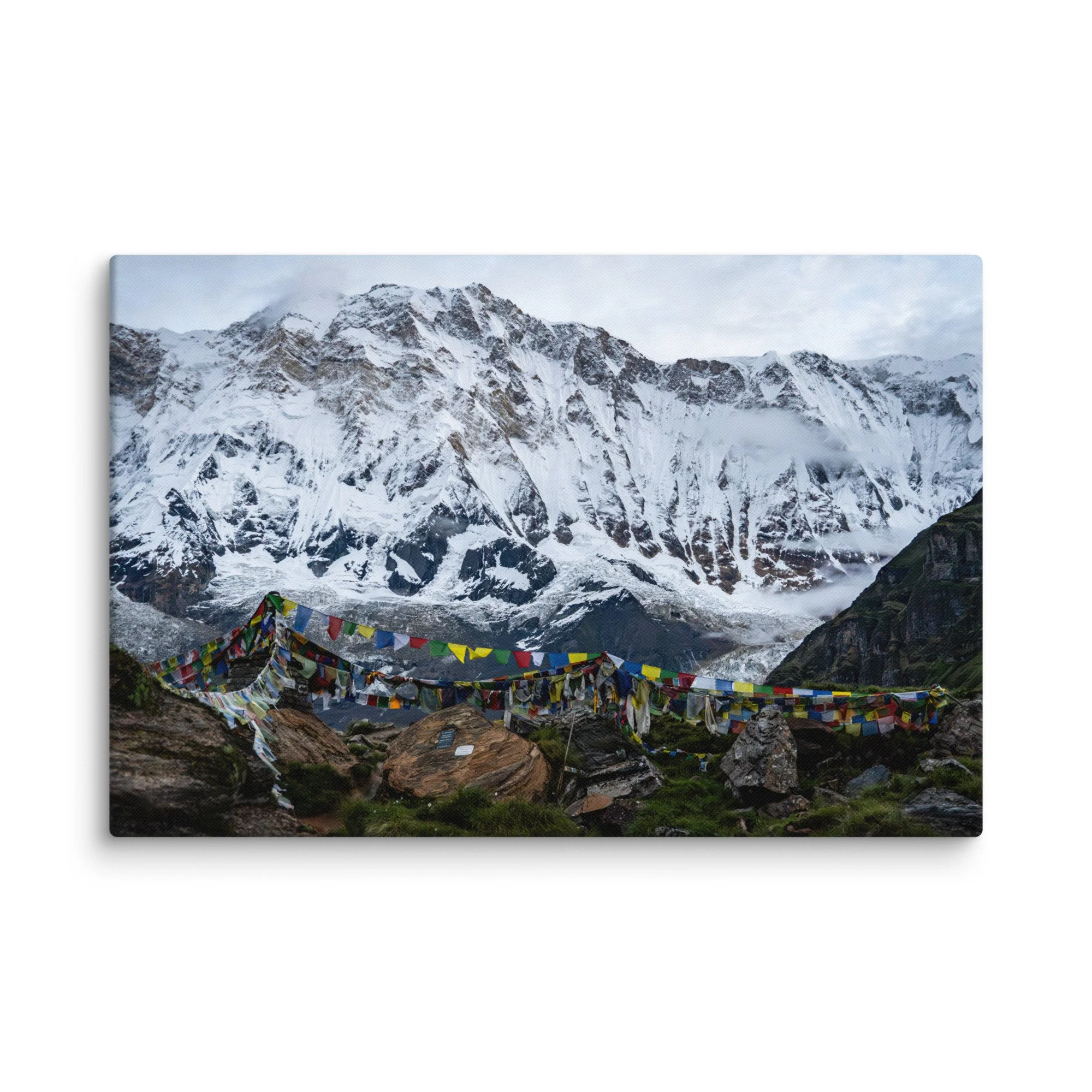 Vibrant multicolored prayer flags in the foreground with towering snow-covered Himalayan peaks and misty sky at Annapurna Base Camp, Nepal – high-altitude spiritual trekking travel