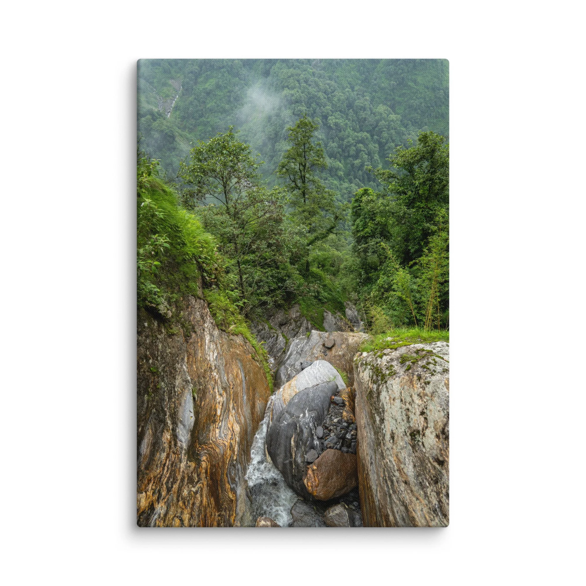 Misty jungle stream cascading over colorful boulders in a lush green gorge on the Annapurna Circuit/Base Camp Trek, Nepal, surrounded by dense forest and fog – high-altitude