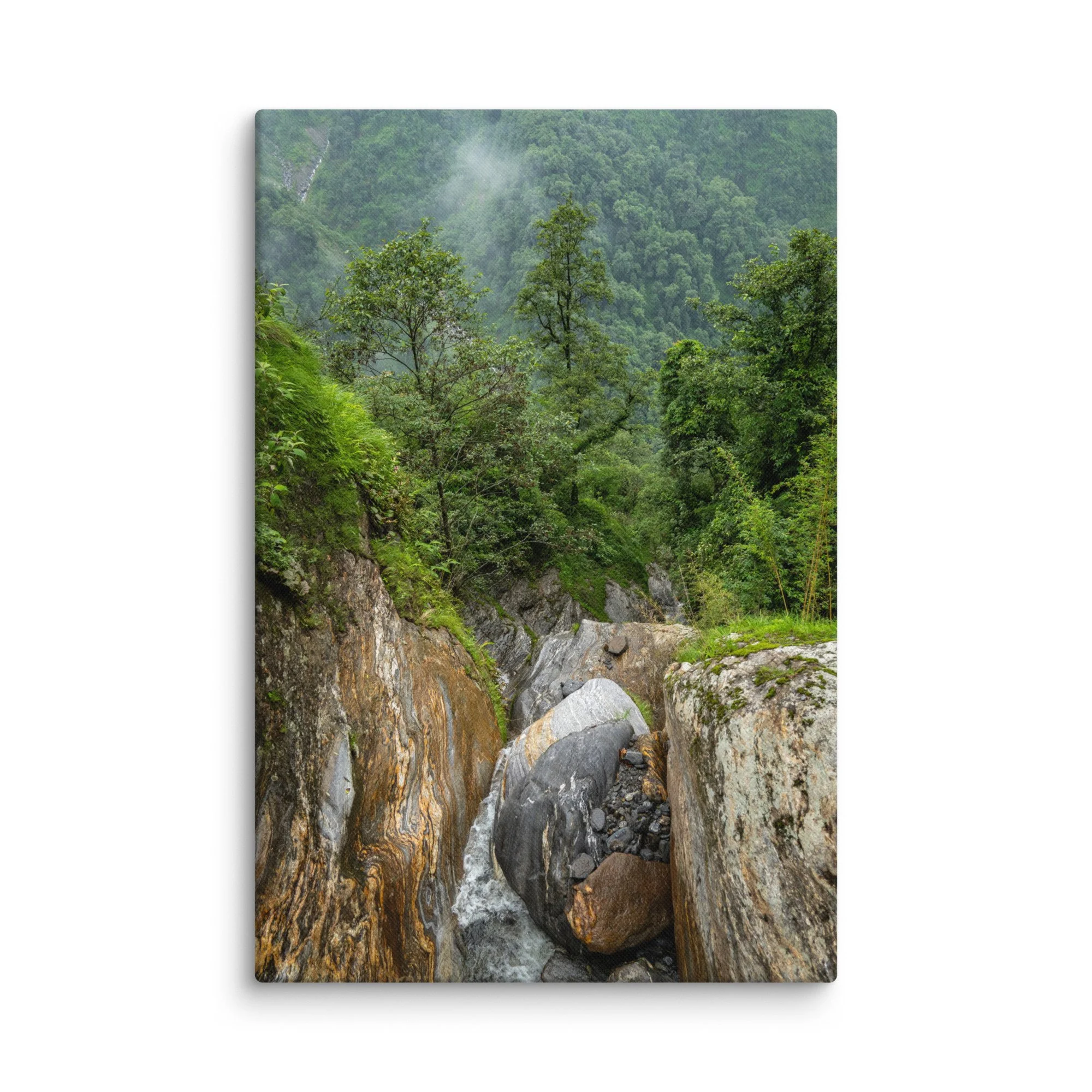Misty jungle stream cascading over colorful boulders in a lush green gorge on the Annapurna Circuit/Base Camp Trek, Nepal, surrounded by dense forest and fog – high-altitude