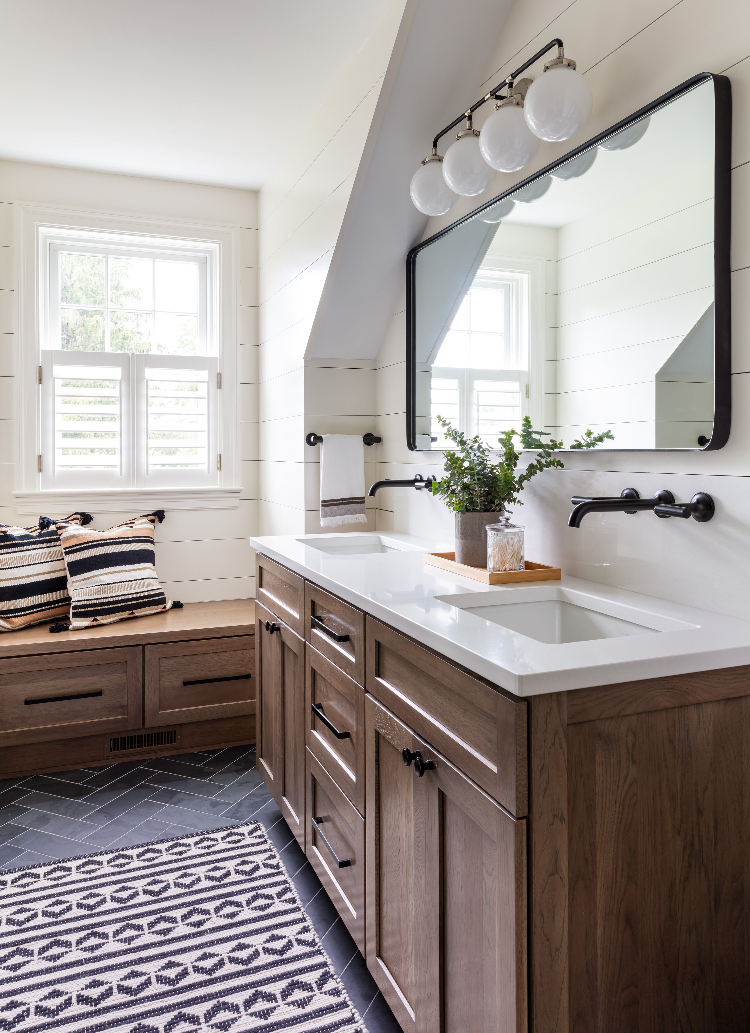 Modern farmhouse bathroom design featuring double vanity with wood cabinets, black fixtures, and shiplap accents for stylish home renovation