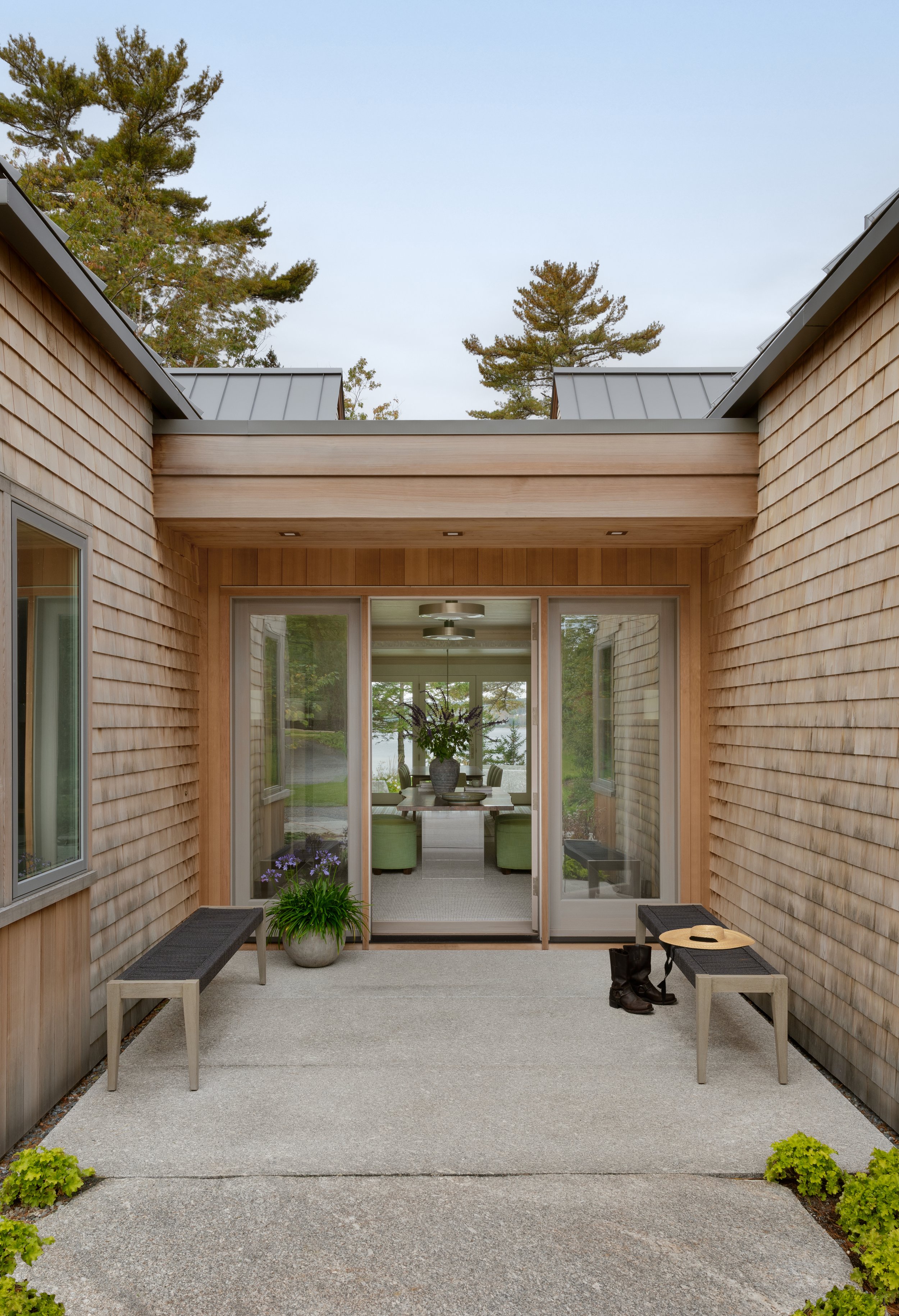 welcoming modern home entry with sliding glass doors benches and planters