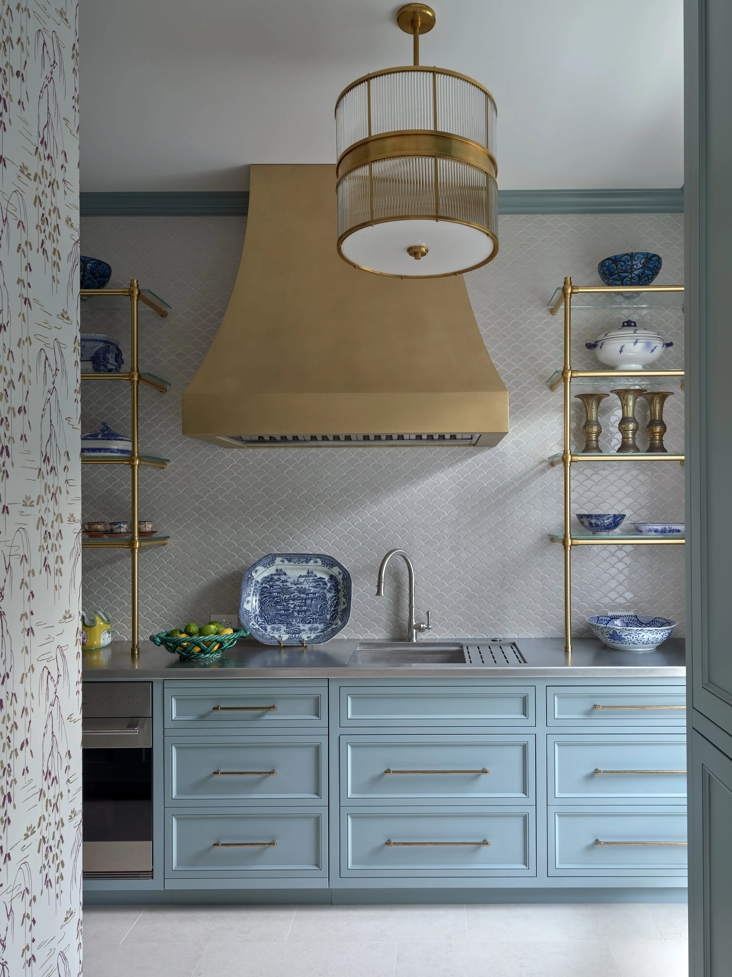 stylish-blue-kitchen-with-gold-custom-vent-hood-elegant-blue-and-white-china-modern-glass-shelf-display.jpg