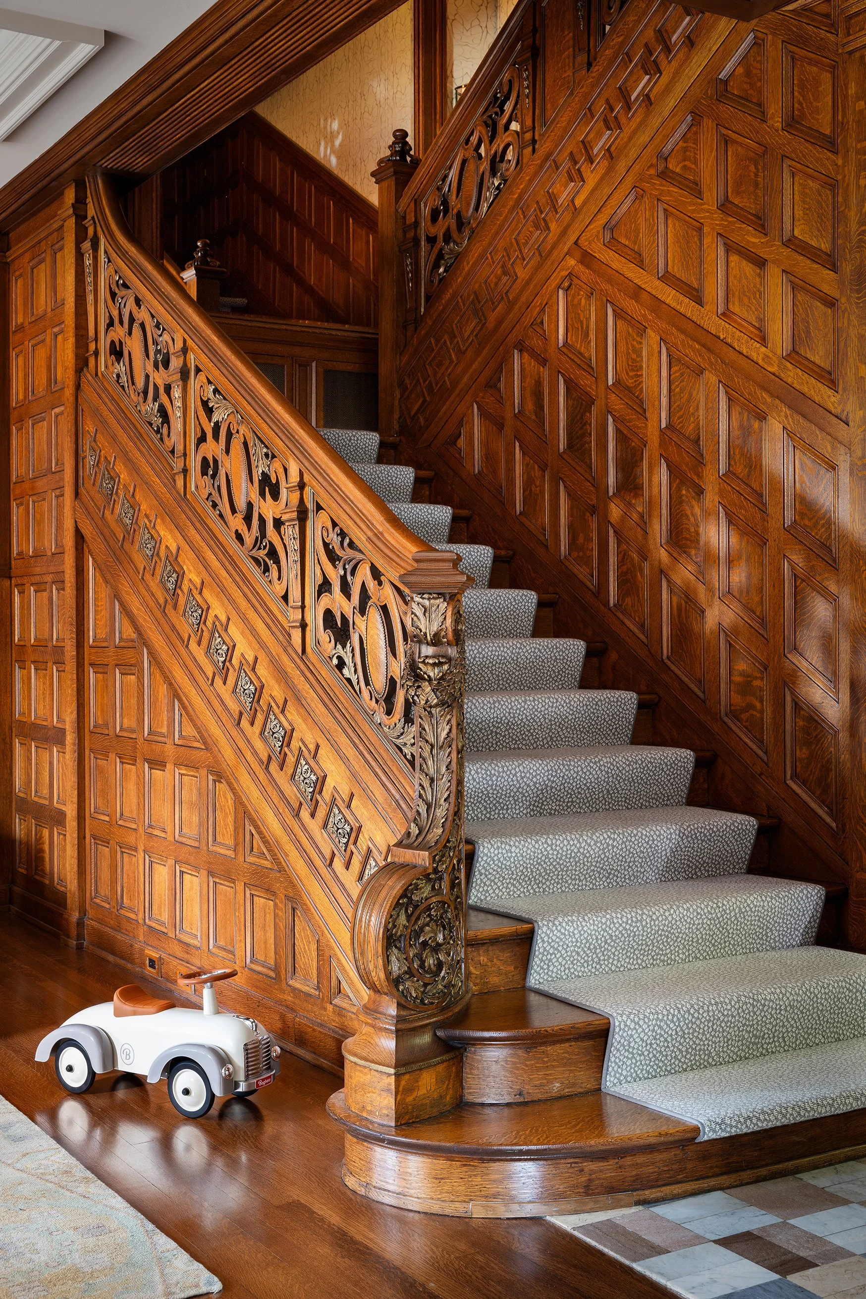 classic staircase with intricate woodwork and soft grey stair runner