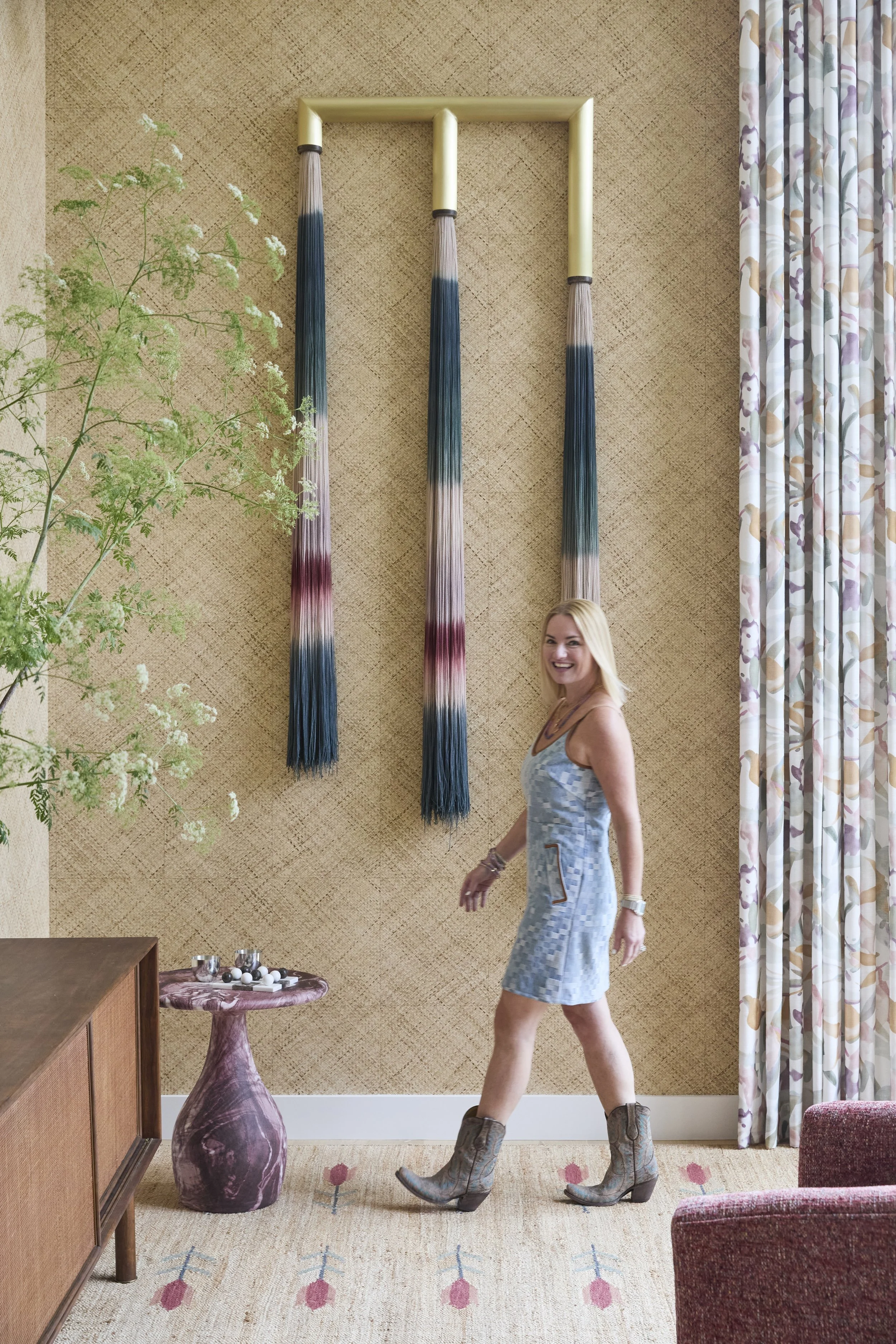 Betsy Wentz in living room with textured yellow walls, colorful curtains, and modern art on the wall.