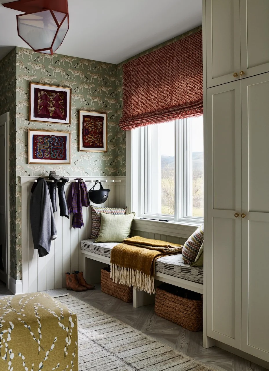 mudroom with leopard wallpaper built in bench rust roman shade framed textile art tall storage cabinets