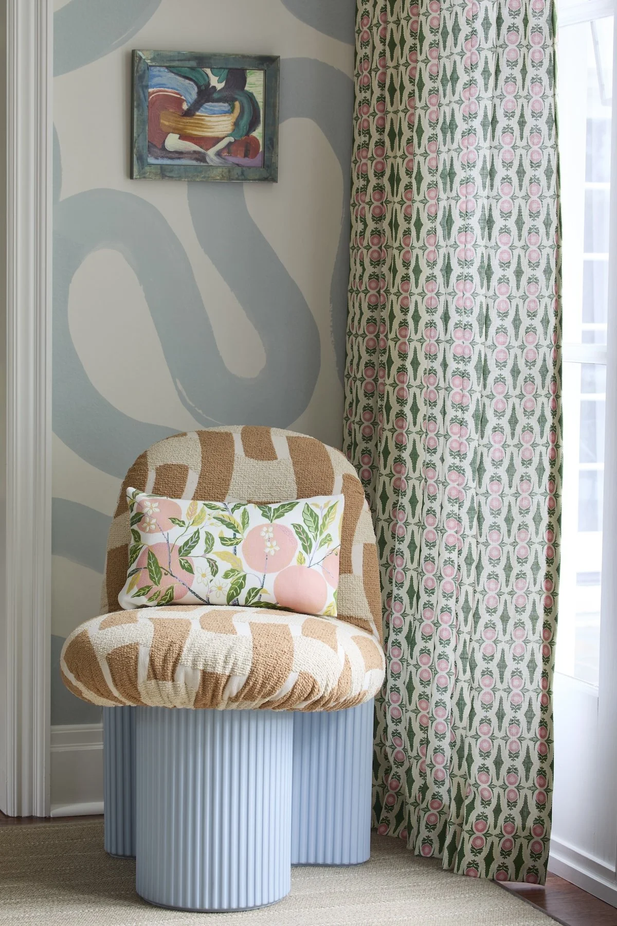 Modern accent chair with tan geometric bouclé, ribbed light blue base, citrus print pillow, blue squiggle wallpaper and patterned curtains by Betsy Wentz