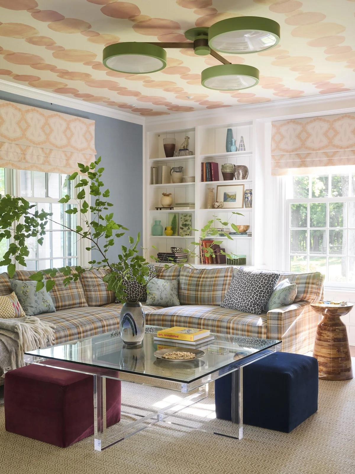 Colorful family room with tan plaid sectional, hand painted peach dot ceiling wallpaper, green three light fixture, acrylic coffee table by Betsy Wentz